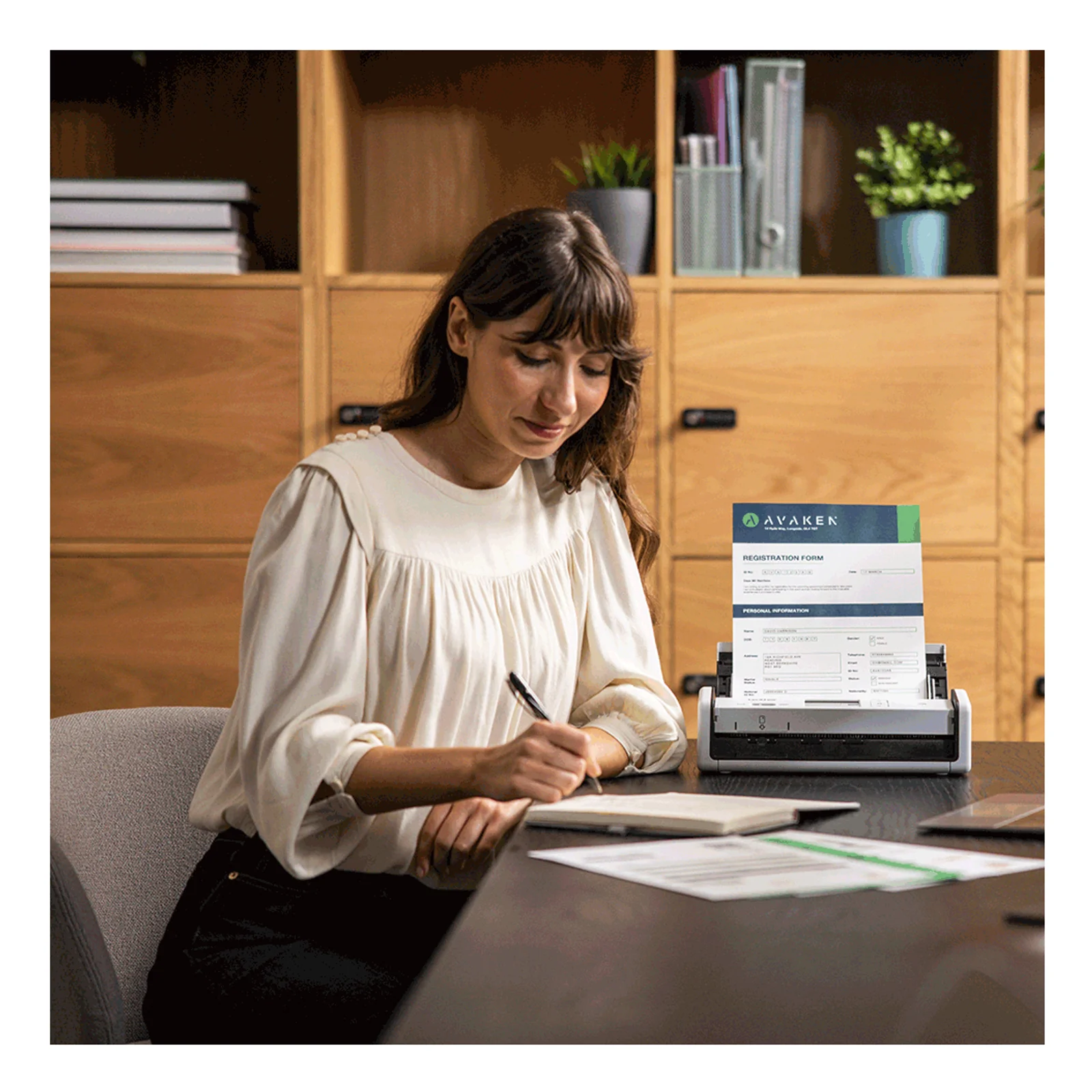 Femme en blouse blanche prenant un document numérisé sur scanner ADS-1800W posé sur un meuble en bois clair