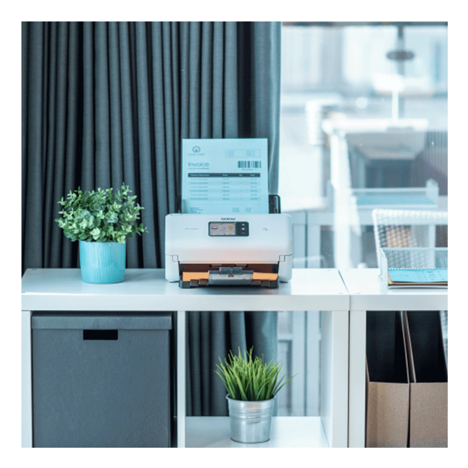 Scanner Brother ADS-4550W posé sur bureau blanc dans bureau moderne avec plante verte et rideaux gris en arrière plan