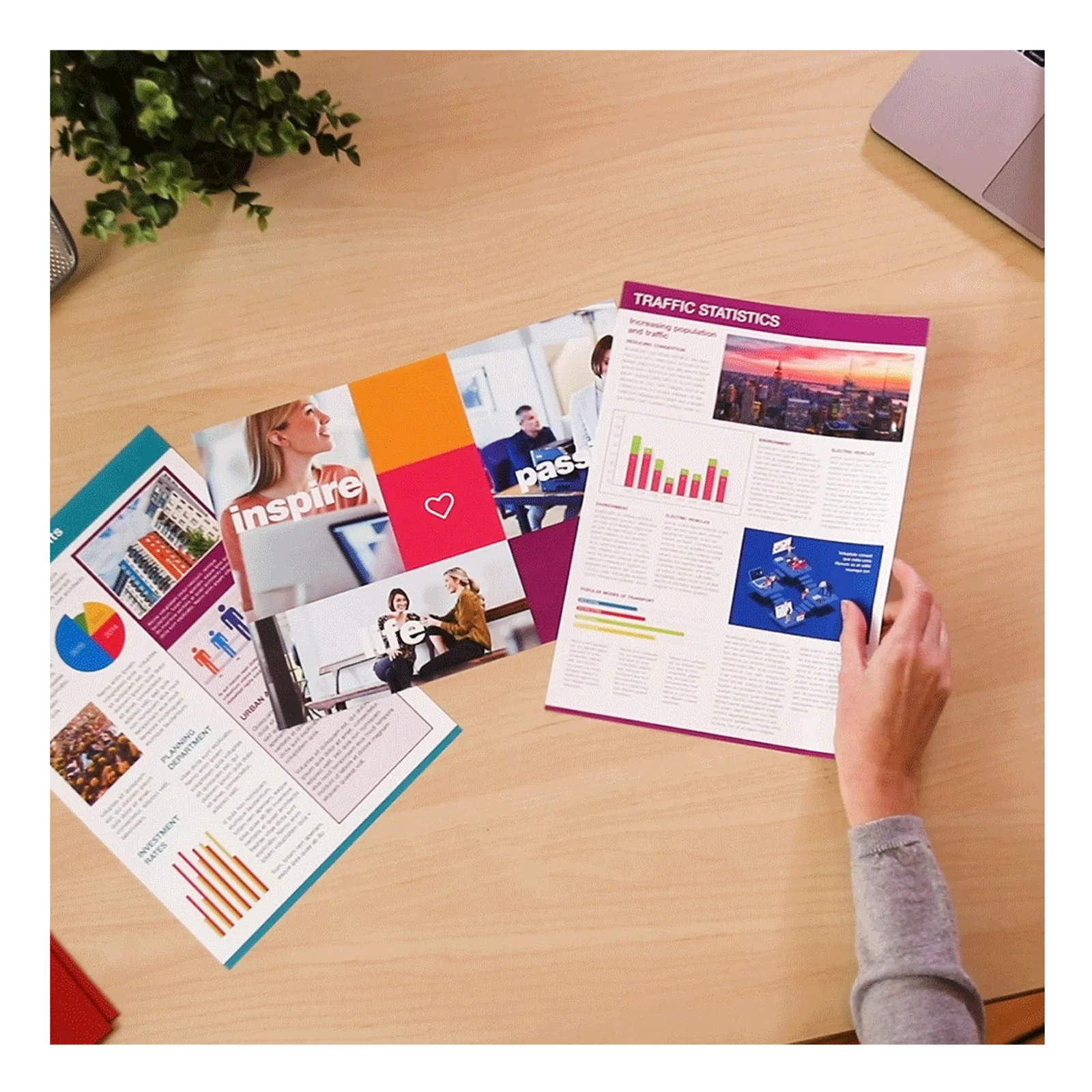 Main feuilletant un rapport couleur intitulé Traffic Statistics imprimé en magenta vif sur un bureau en bois clair