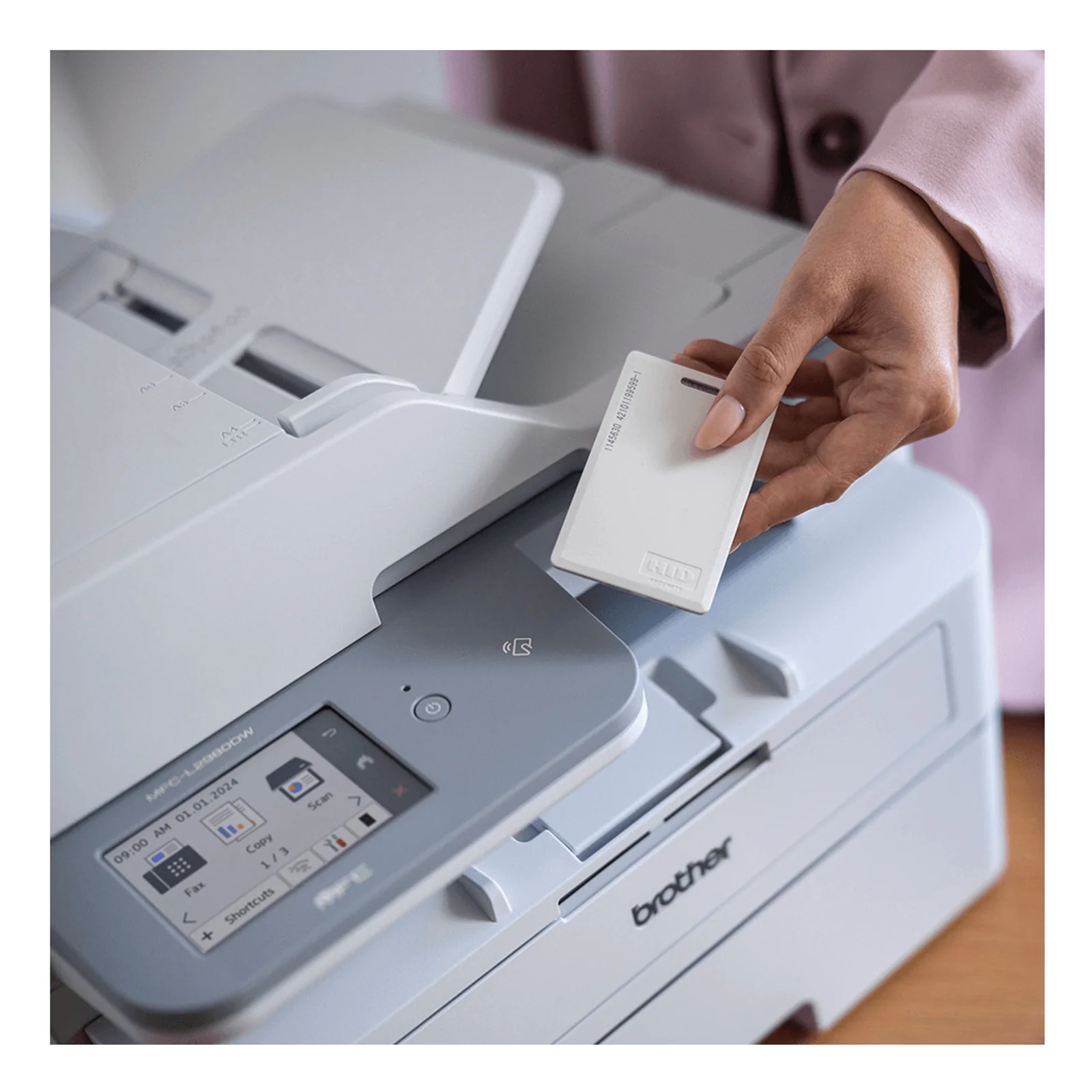 Main approchant une carte d'authentification HID du lecteur NFC du multifonction MFC-L2980DW pour libérer une impression sécurisée