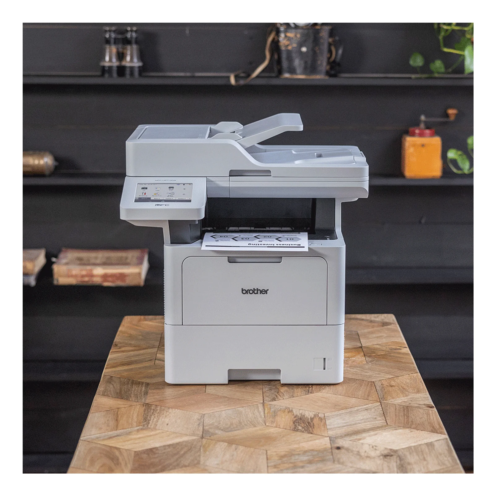 Multifonction Brother MFC-L6710DW posé sur une table en bois avec document en sortie, dans un intérieur sombre type loft