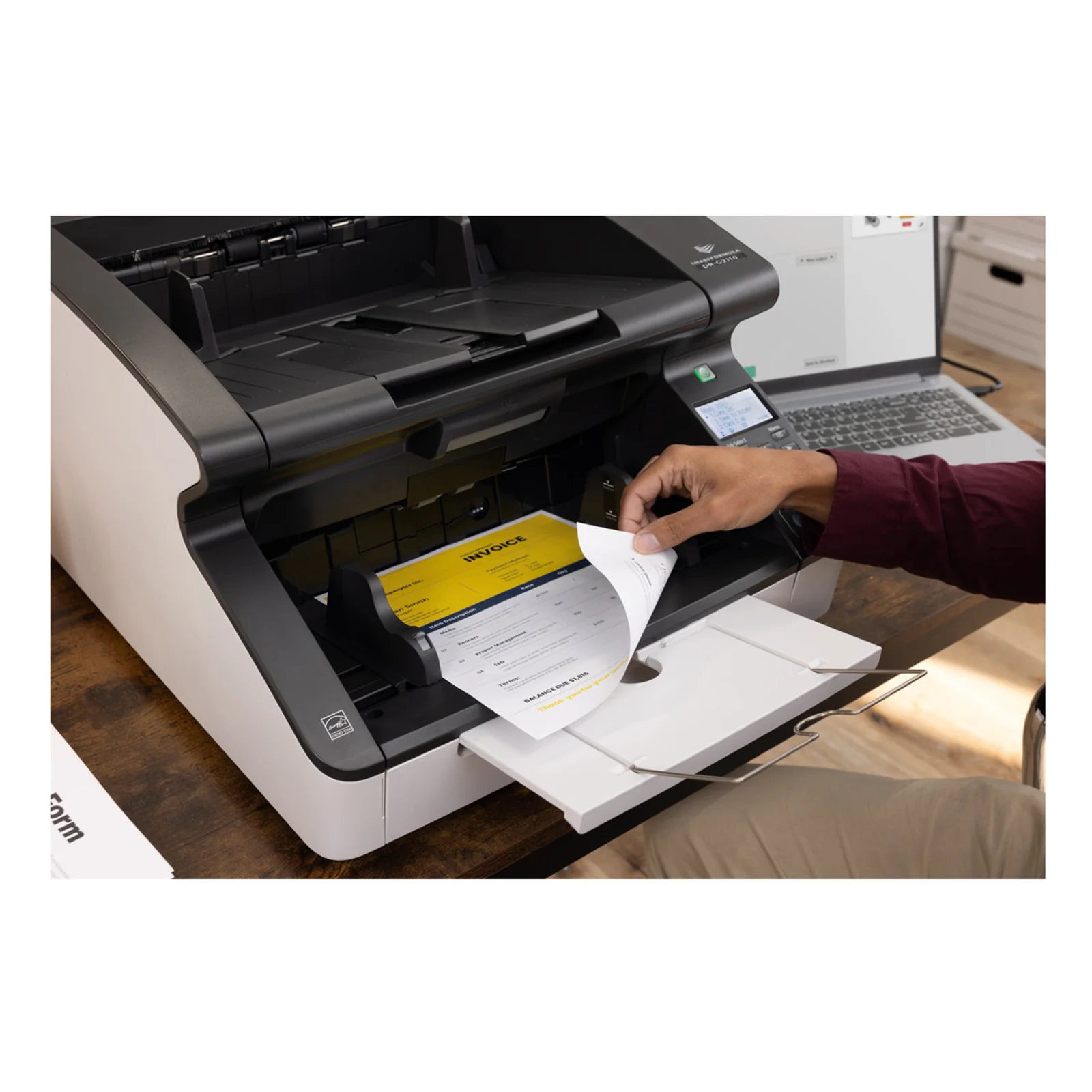 Opérateur récupérant une pile de pages numérisées en sortie du DR-G2110 connecté à un ordinateur portable