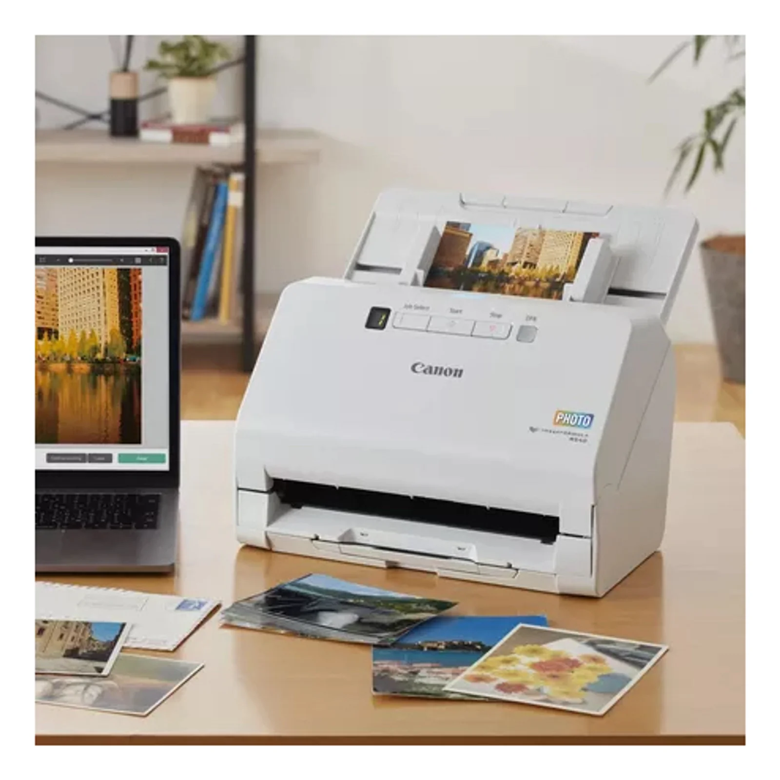 Mise en situation du scanner RS40 dans un bureau avec photos imprimées tirages cartes postales et logiciel ouvert sur un portable