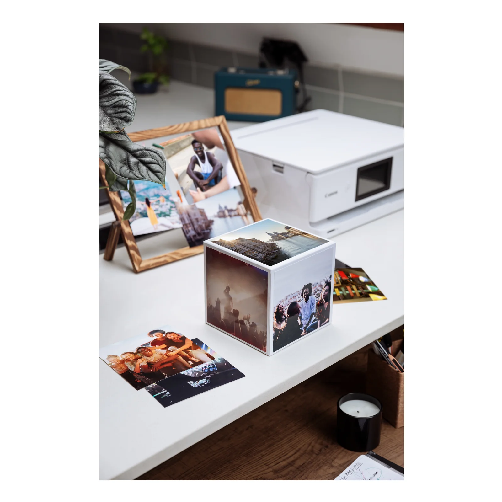 Cube photo Canon avec clichés de voyage devant une imprimante PIXMA et un cadre bois