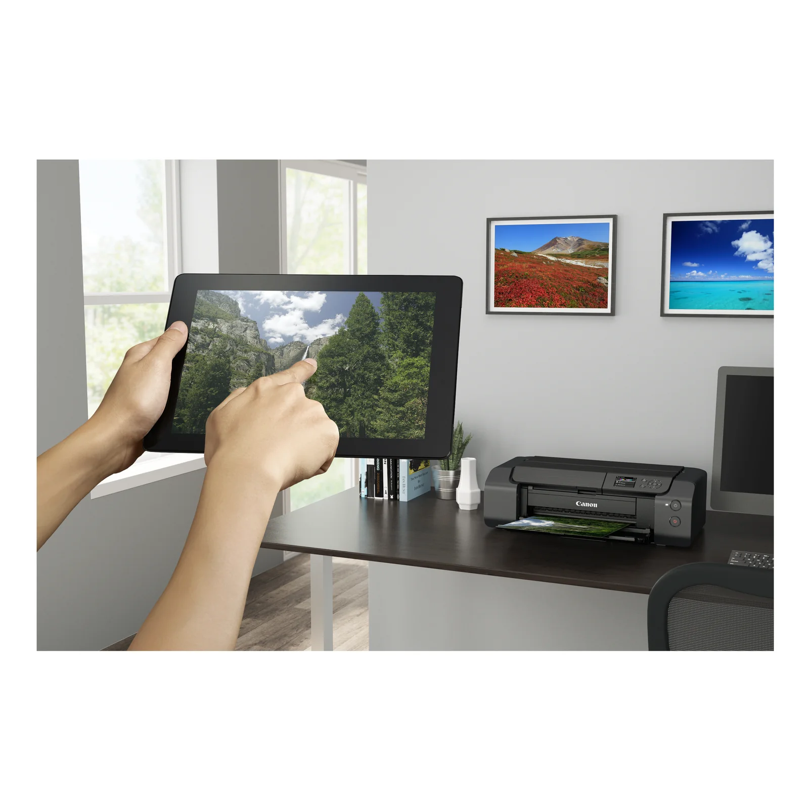 Mains tenant une tablette montrant une cascade, PIXMA PRO-200S en arrière-plan sur le bureau