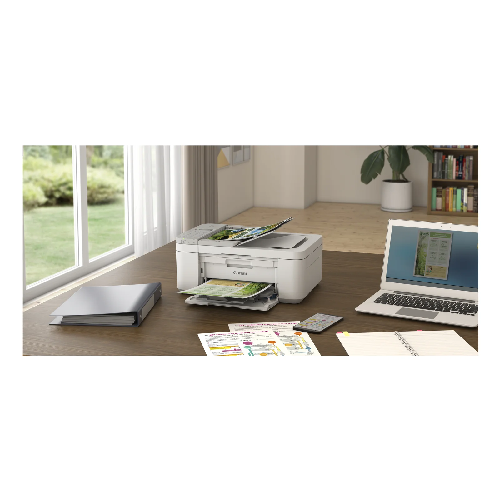 Canon PIXMA TR4756i posée sur un bureau en bois entre un classeur, un ordinateur portable et un cahier