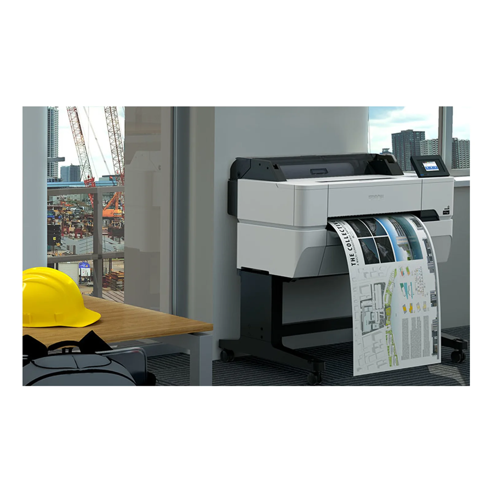 Mise en situation du traceur Epson 24 pouces dans un bureau de chantier avec sortie de plans couleur et casque de chantier jaune au premier plan