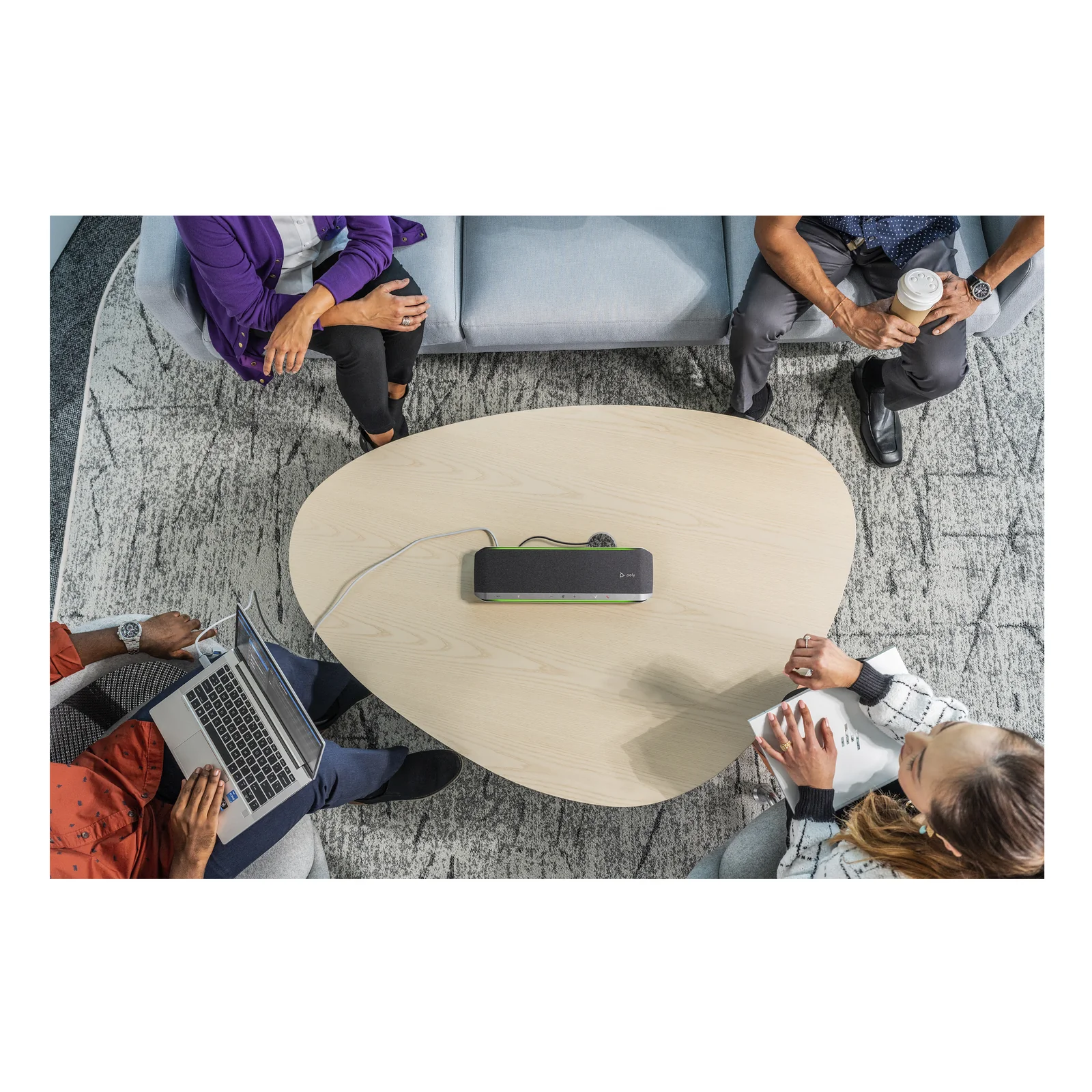 Vue aérienne d'une réunion de 4 personnes autour d'une table basse en bois, le Poly Sync 60 posé au centre de la table