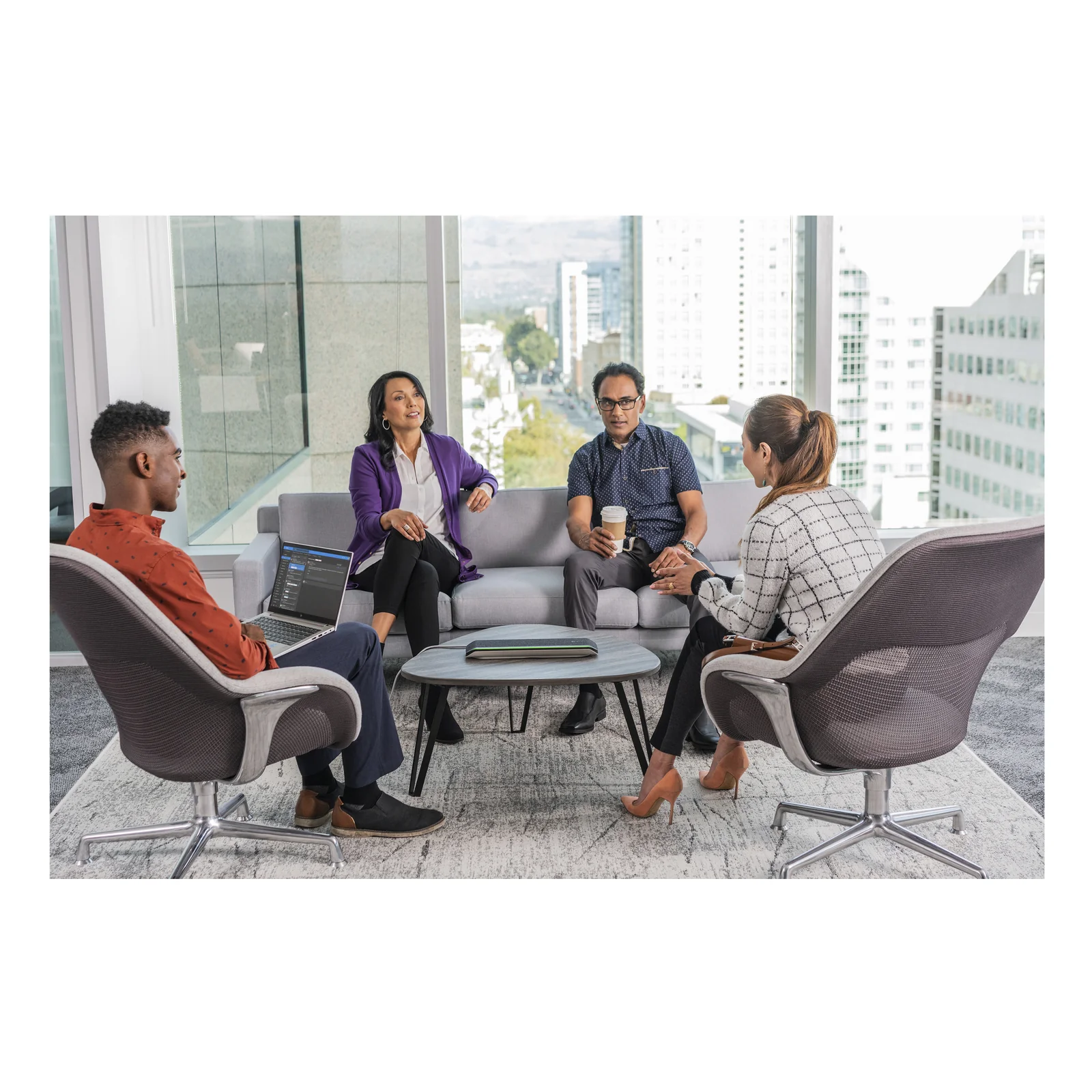 4 professionnels en réunion informelle dans un espace lounge, discussion animée autour d'une table basse