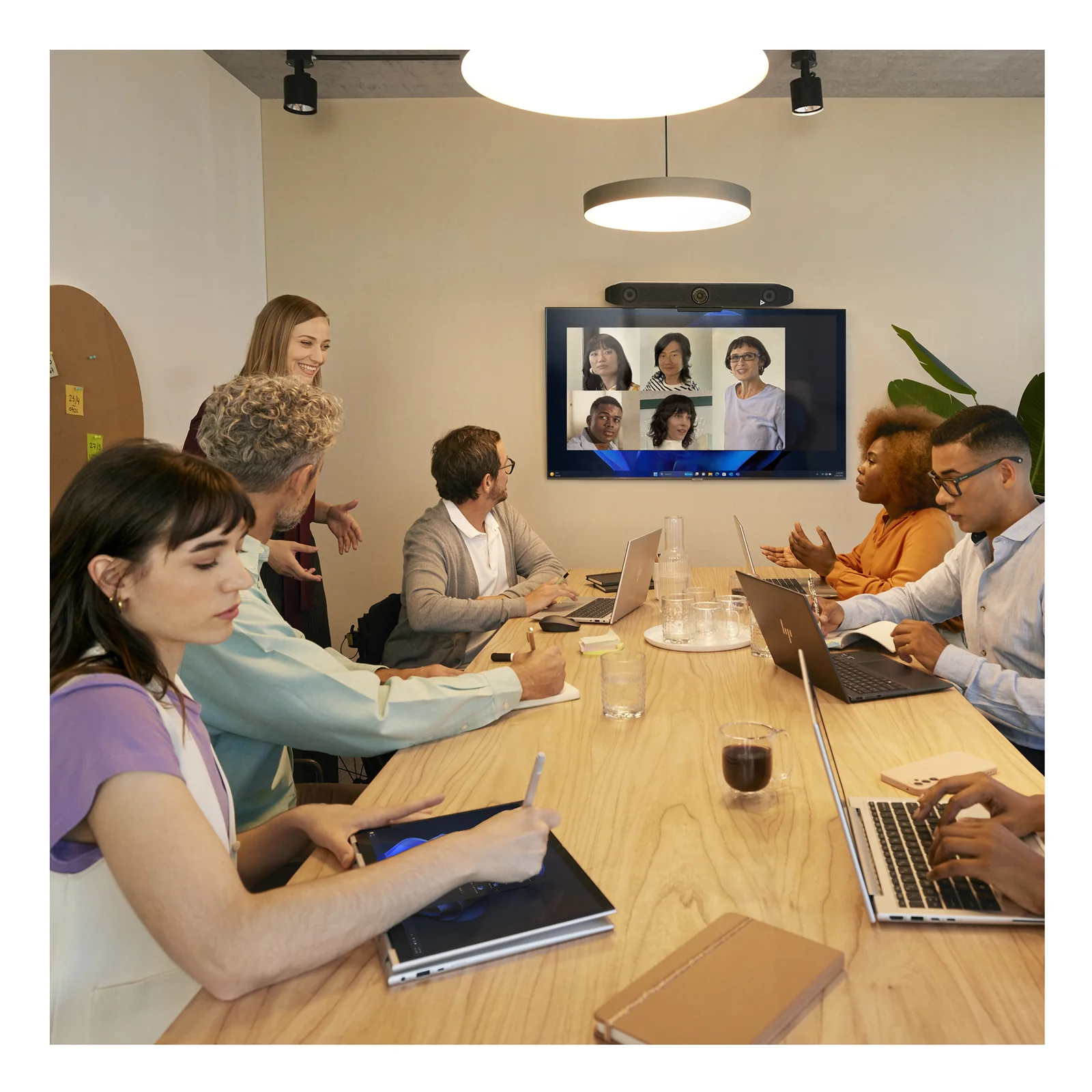 Salle de réunion avec la Poly Studio V52 fixée sur TV murale, équipe autour d'une grande table en visioconférence Teams.