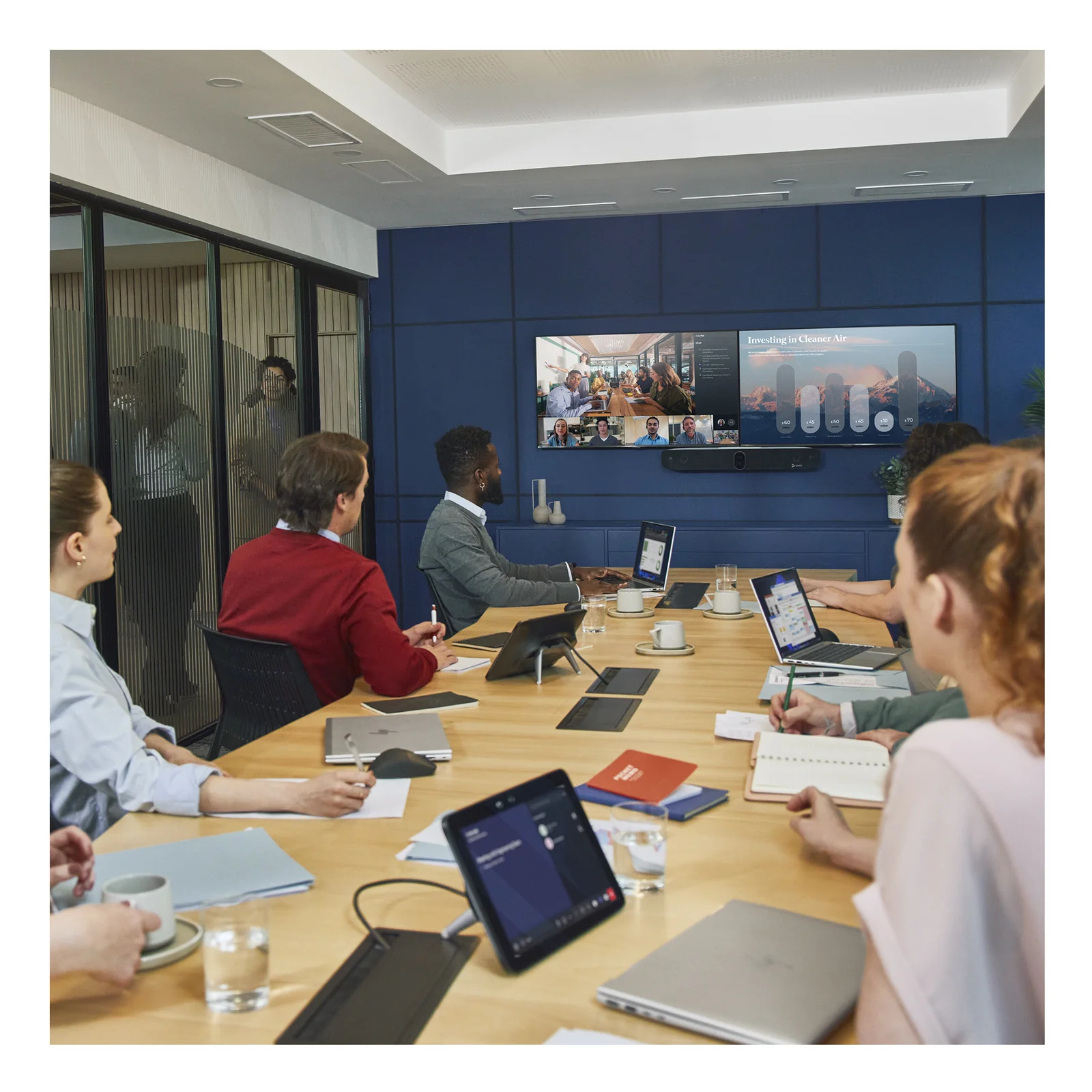 Salle de conférence avec HP Poly Studio X72 montée sur écran, groupe de collaborateurs en réunion hybride avec participants à distance affichés