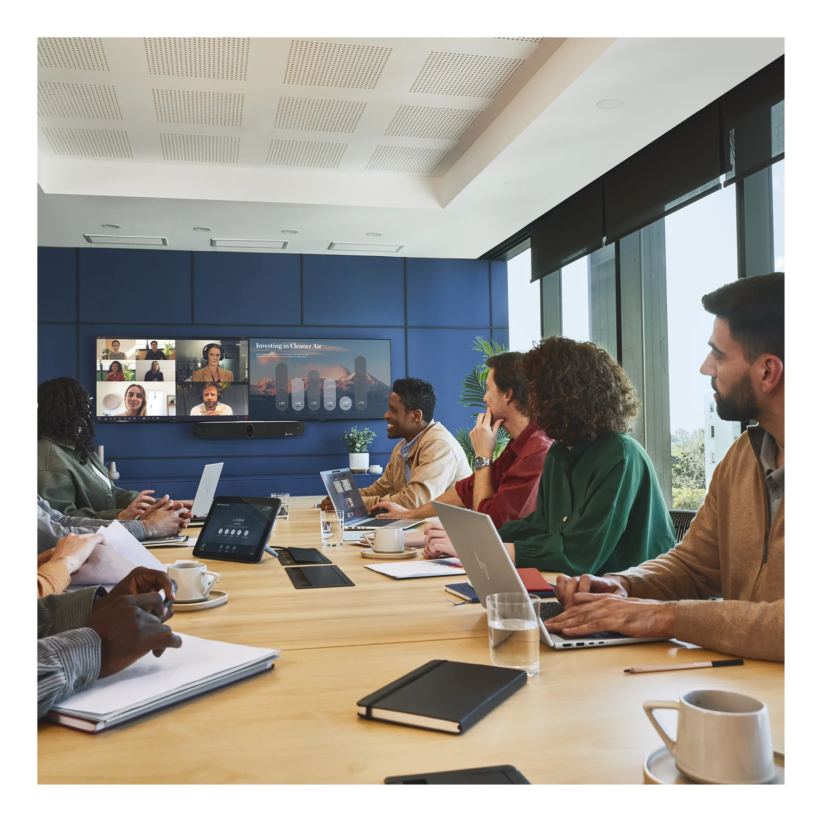 Grande salle de réunion avec HP Poly Studio X72 en fonctionnement, participants autour d'une table et visioconférence active sur double écran mural