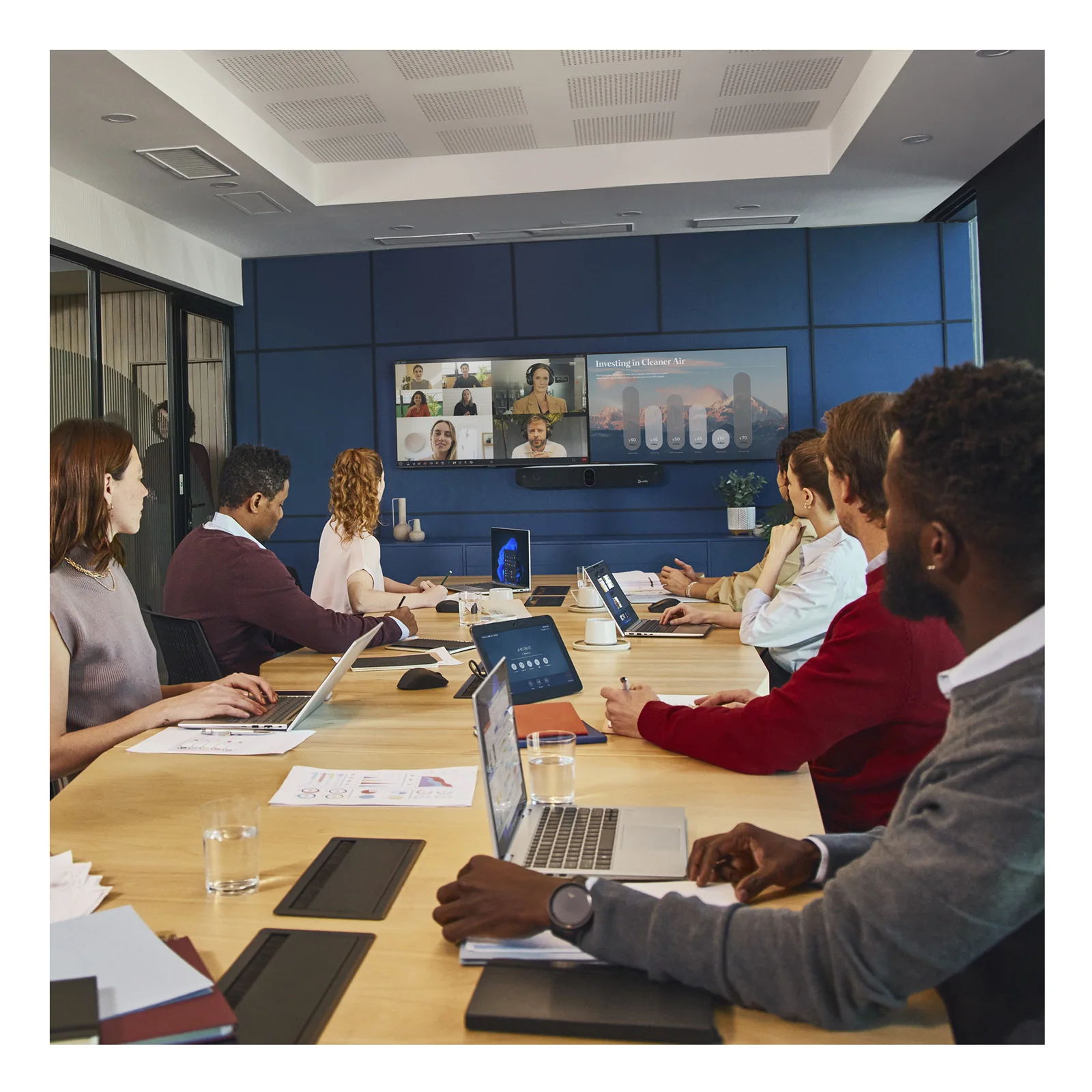 Salle de conférence vue de côté avec HP Poly Studio X72 sur écran, collaborateurs en réunion hybride avec appel vidéo actif