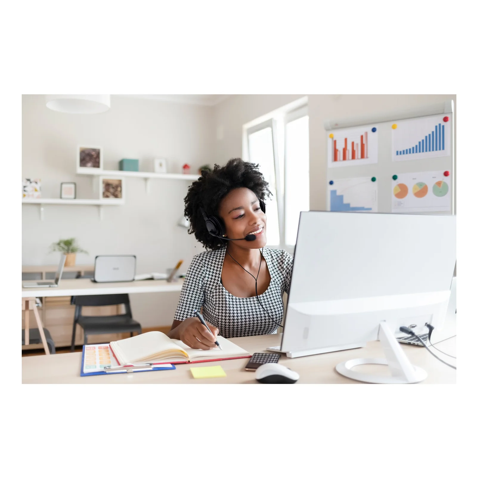 Femme portant un casque audio noir, travaillant à un bureau face à un écran