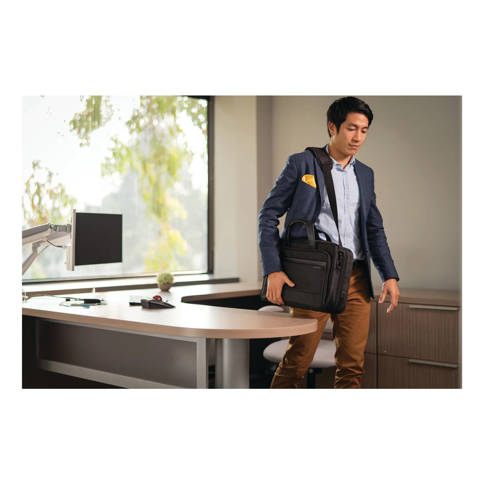 Professionnel en veste portant la Kensington Contour 2.0 à l'épaule dans un bureau
