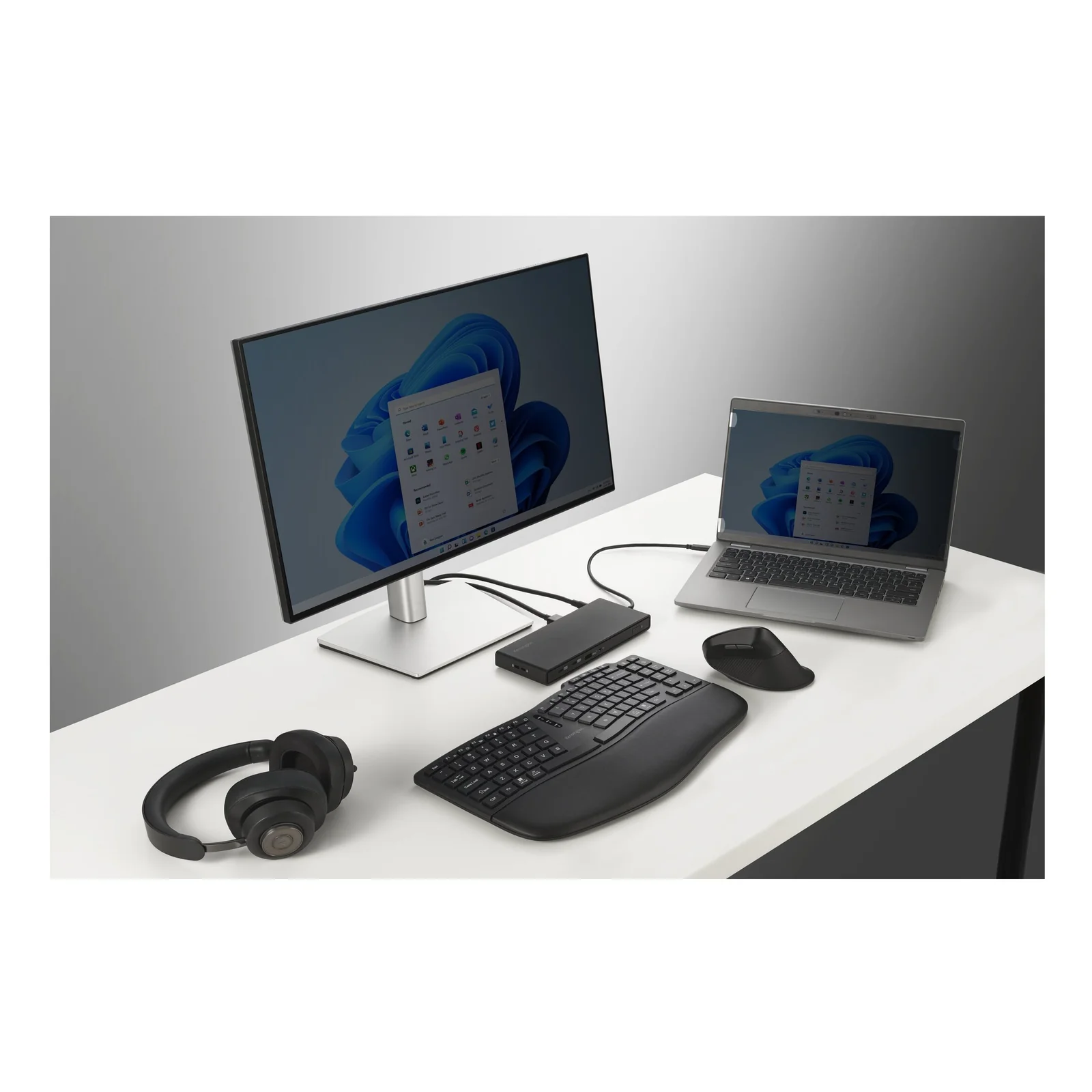 Bureau avec PC portable branché sur moniteur externe, casque audio, clavier et souris