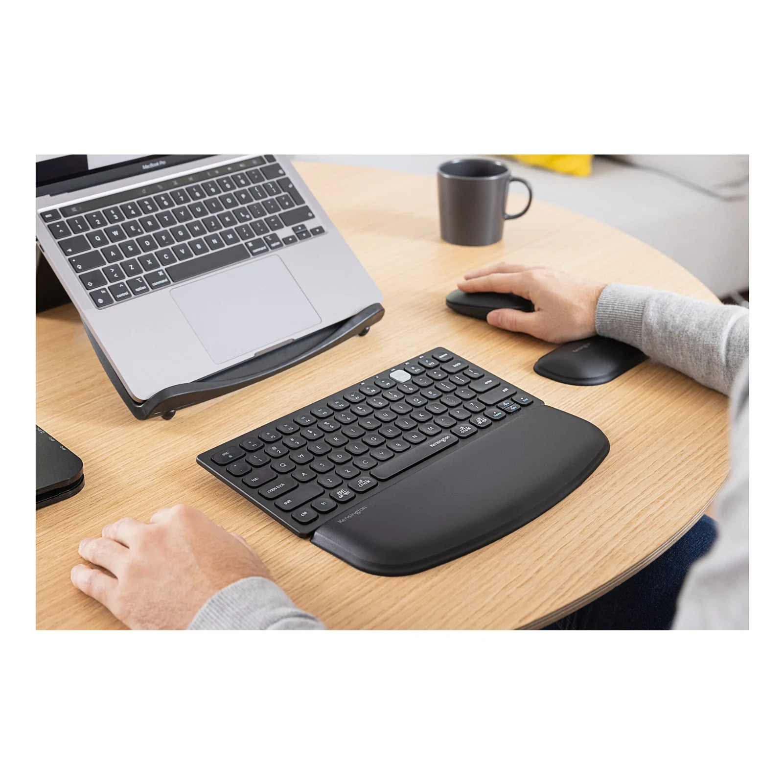 Personne utilisant un clavier avec repose-poignet Kensington ErgoSoft, bureau bois