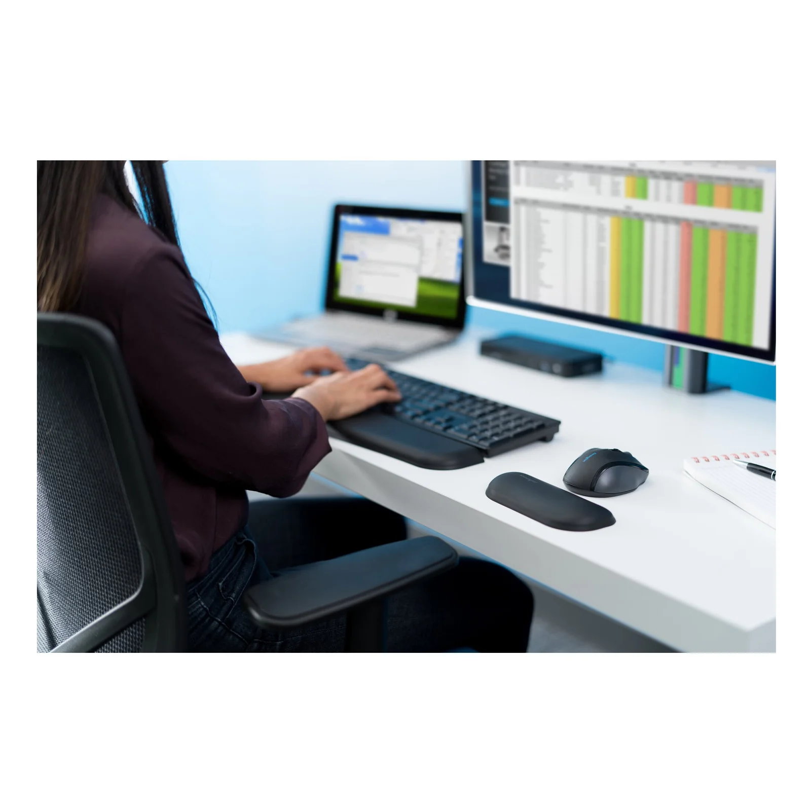 Femme au bureau avec double moniteur, configuration clavier souris et repose-poignet