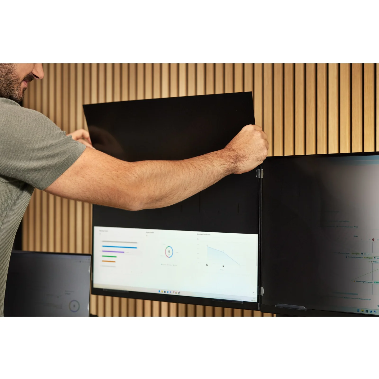Personne retirant un grand panneau de filtre sombre d'un moniteur, mains tenant le filtre par les bords