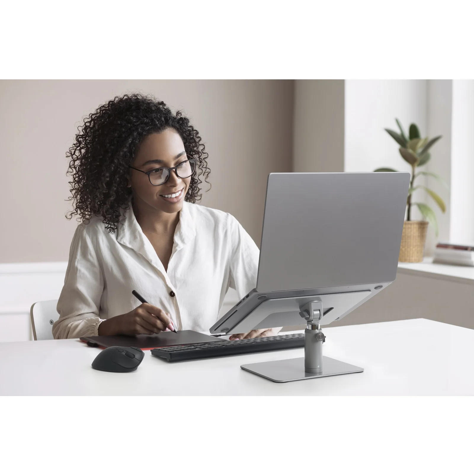 Femme travaillant sur un laptop surélevé par le rehausseur, contexte bureau