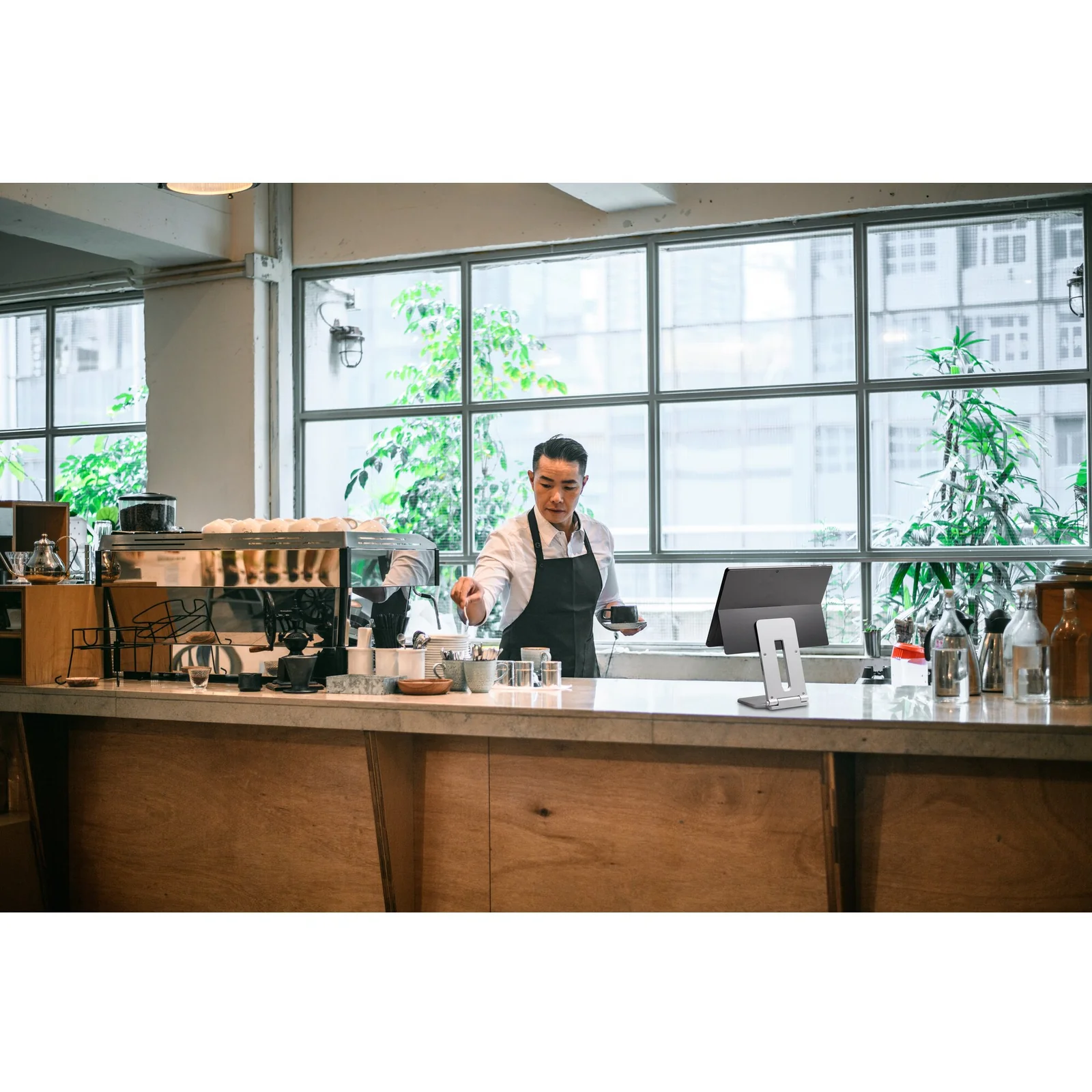 Comptoir café, opérateur utilisant une tablette sur stand, ambiance espace commercial