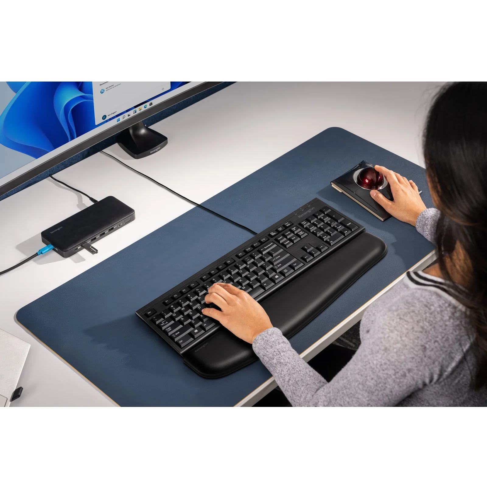 Vue plongeante d'un poste de travail avec clavier filaire Kensington et grand tapis de bureau bleu