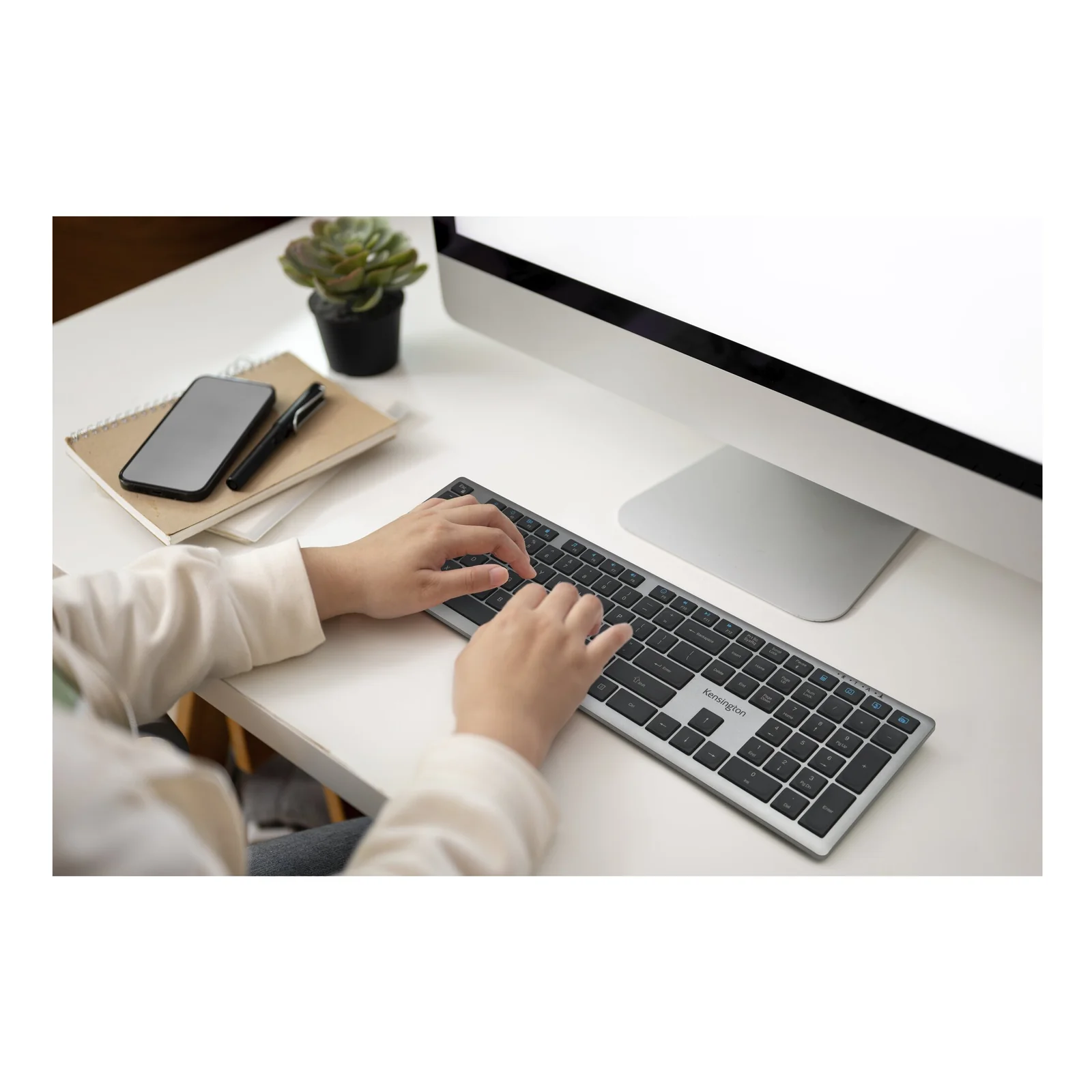 Personne tapant sur le KB535 EQ posé sur un bureau blanc, vue légèrement en plongée