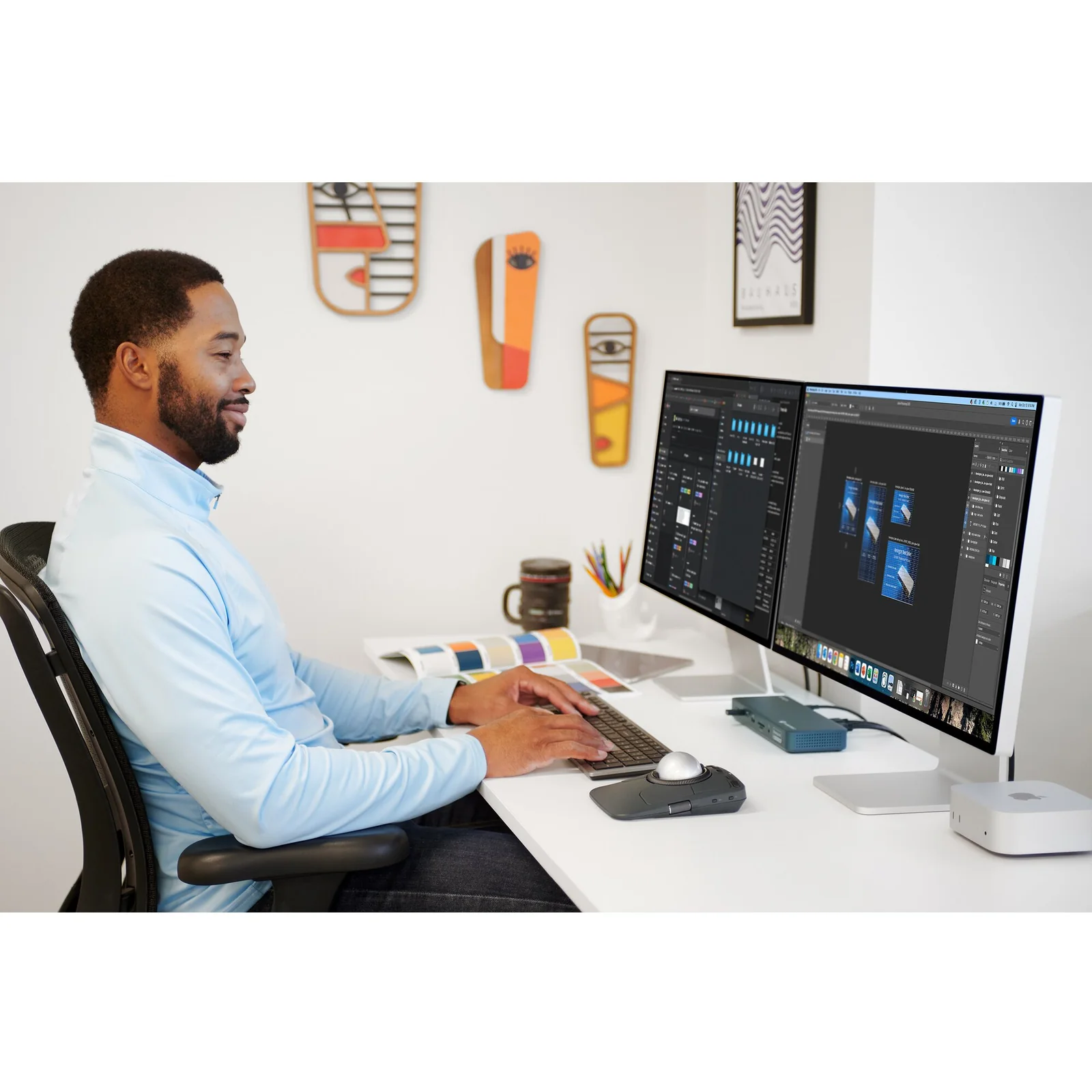 Homme au bureau face à un grand écran, KB535 EQ et souris Kensington posés sur le bureau