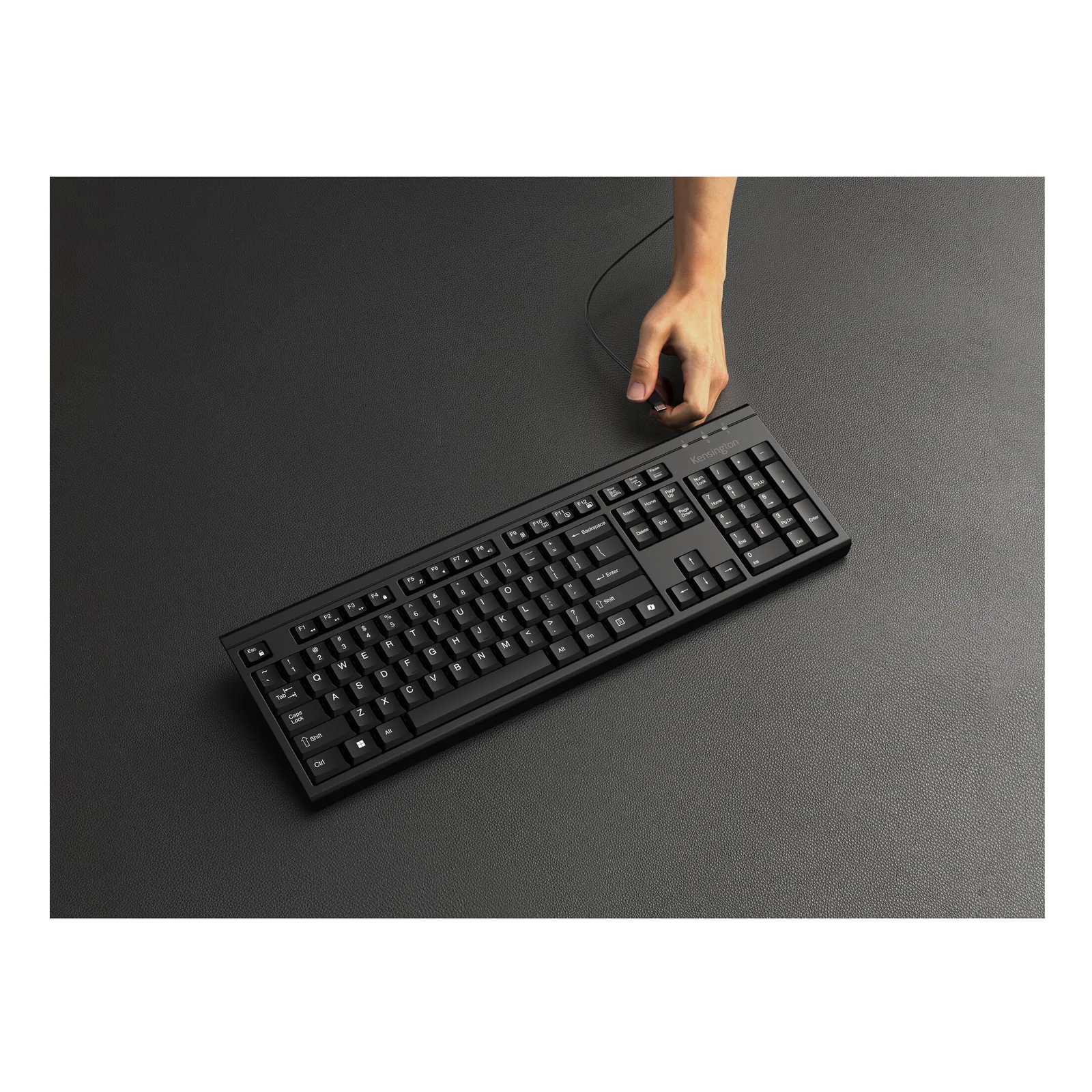 Vue de dessus du clavier Kensington KM270 EQ noir sur bureau sombre, main posée à côté