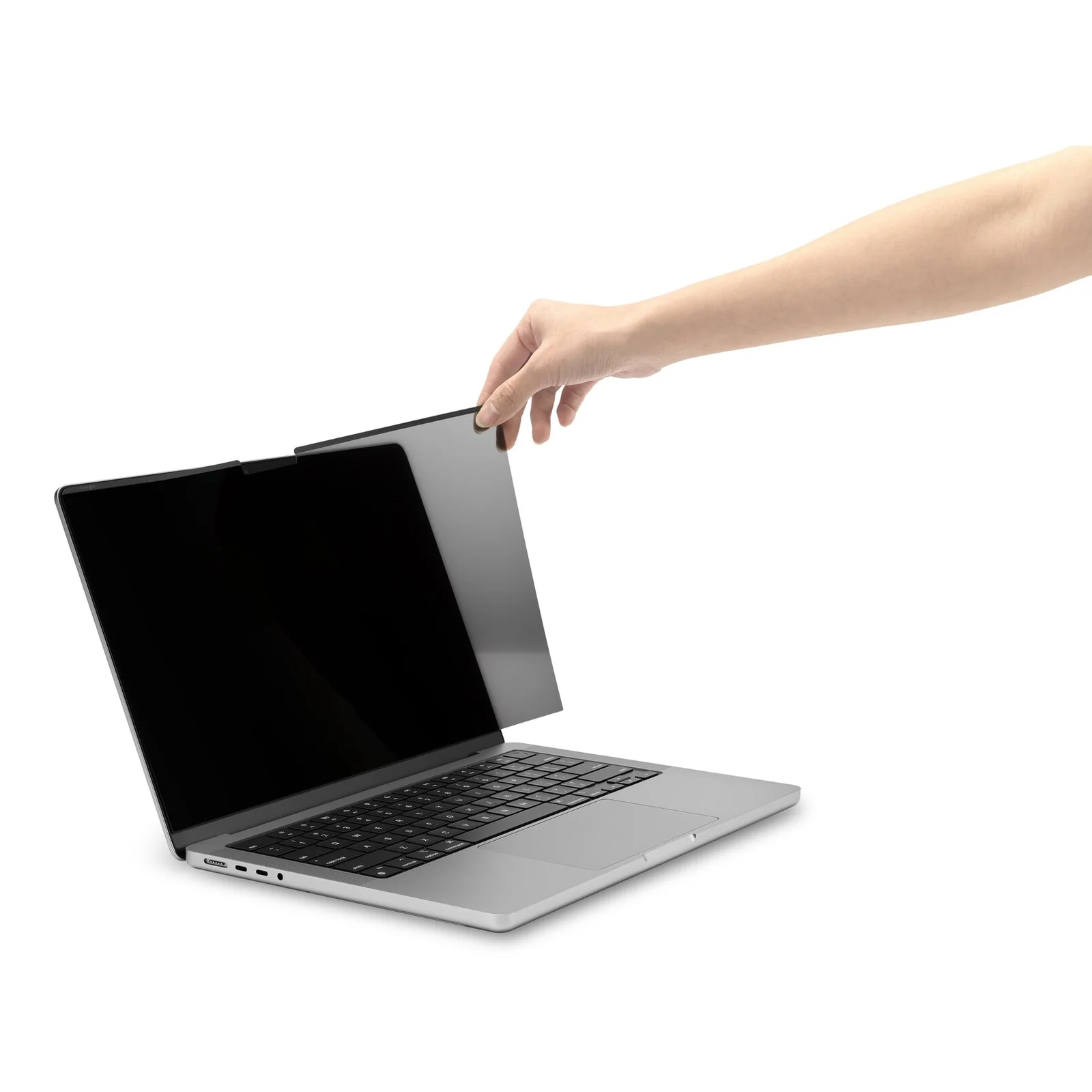 Main approchant le filtre de confidentialité magnétique Kensington d'un MacBook Pro ouvert, vue de face