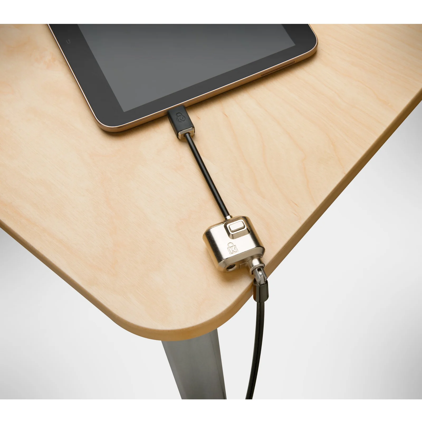 Câble Kensington MiniSaver Mobile sécurisant une tablette sur un bureau en bois, vue de dessus
