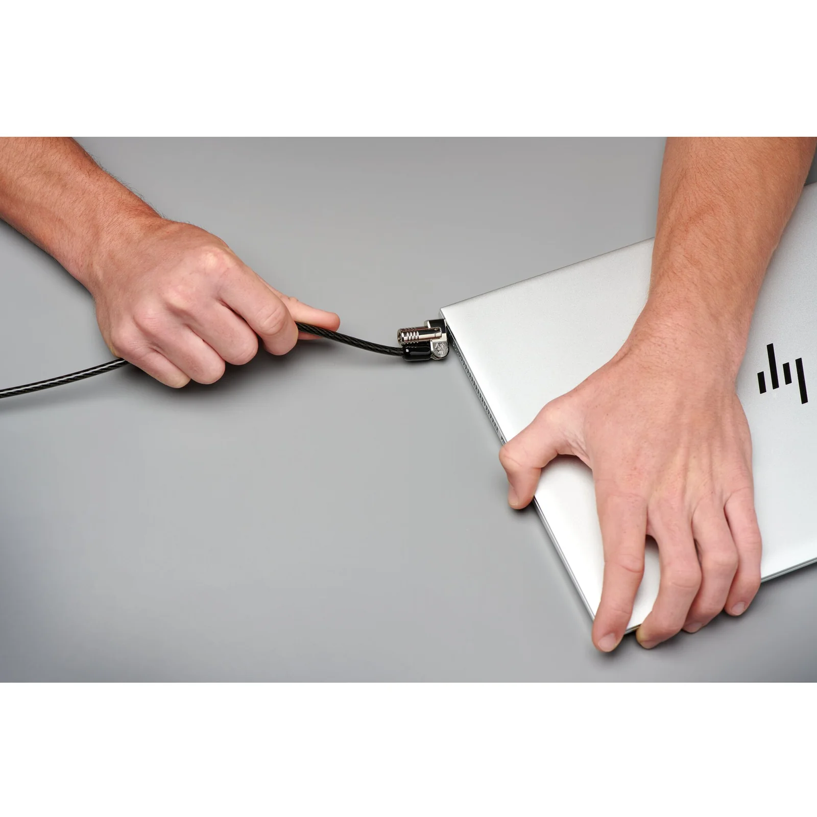 Mains insérant le verrou NanoSaver dans le slot d'un ordinateur portable fin argenté