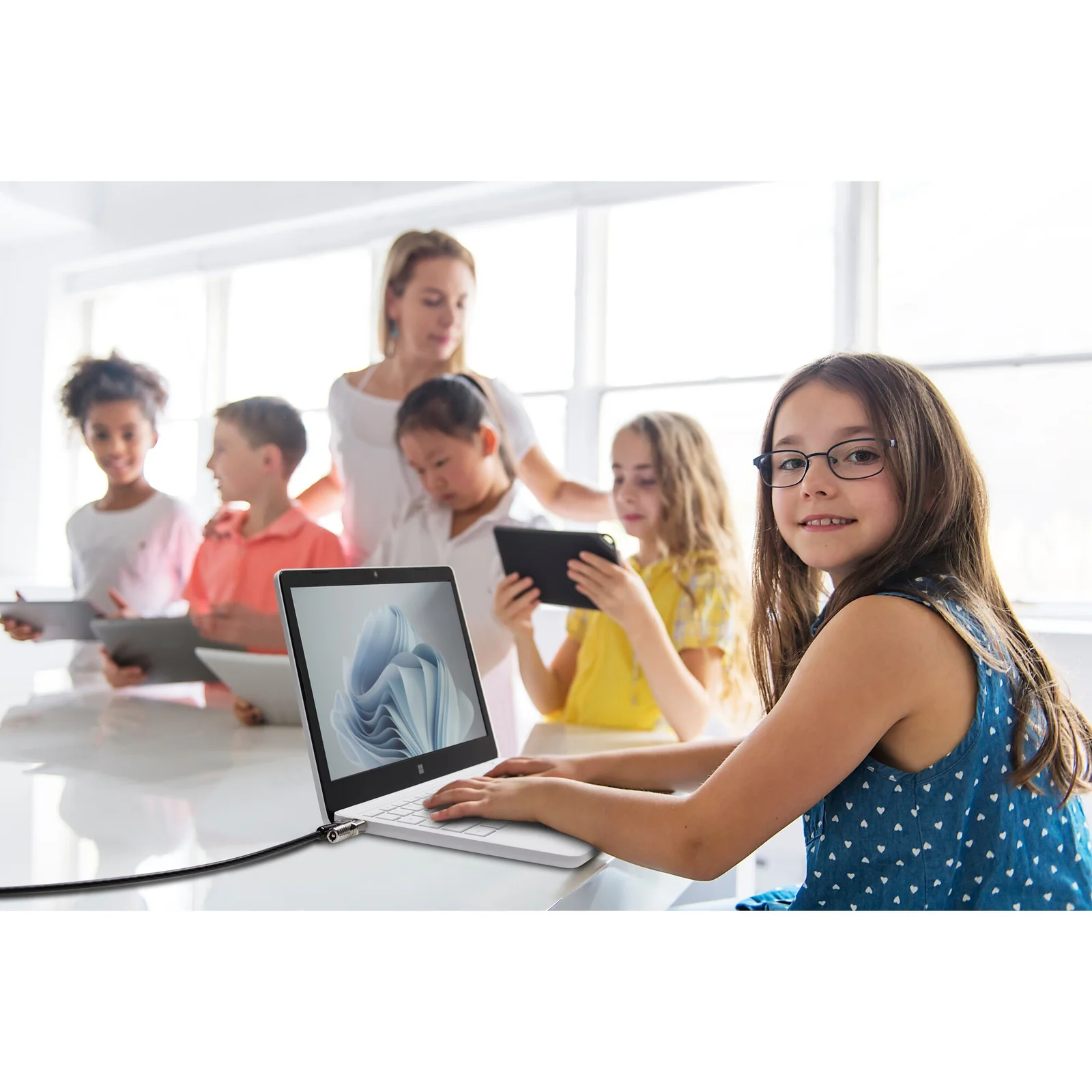 Salle de classe avec enseignante et élèves utilisant des tablettes et ordinateurs portables
