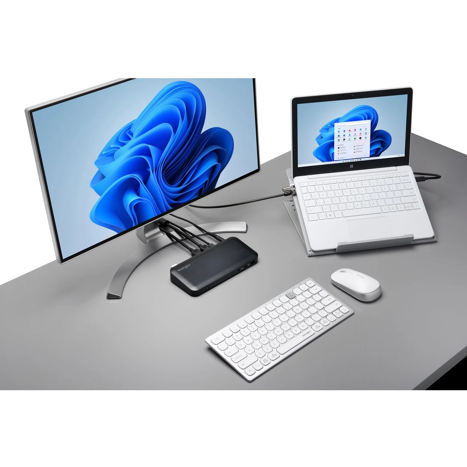 Station de travail avec ordinateur portable en dock, grand écran, clavier et souris sur bureau gris