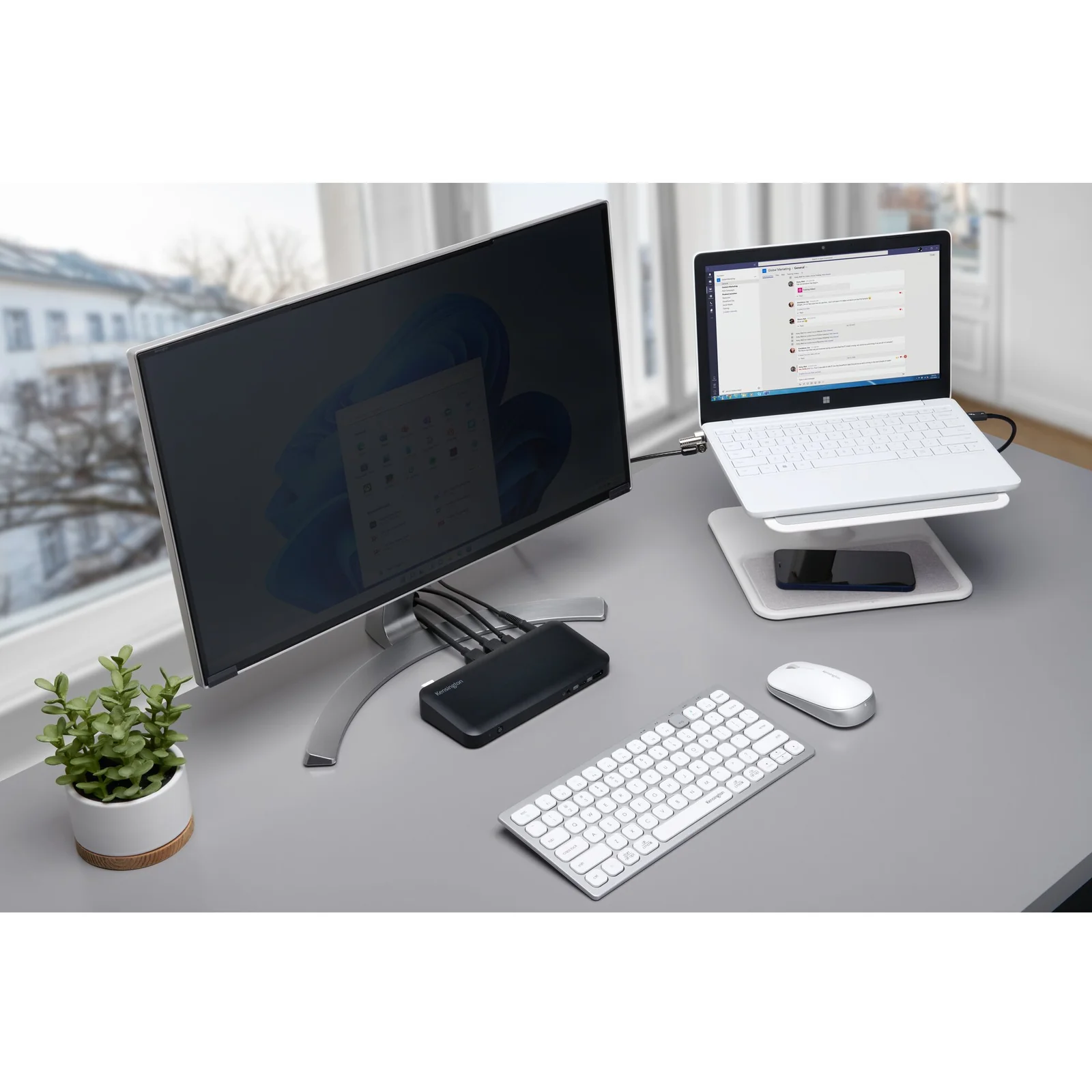 Bureau avec écran sur bras articulé, ordinateur portable sur rehausseur et clavier sans fil