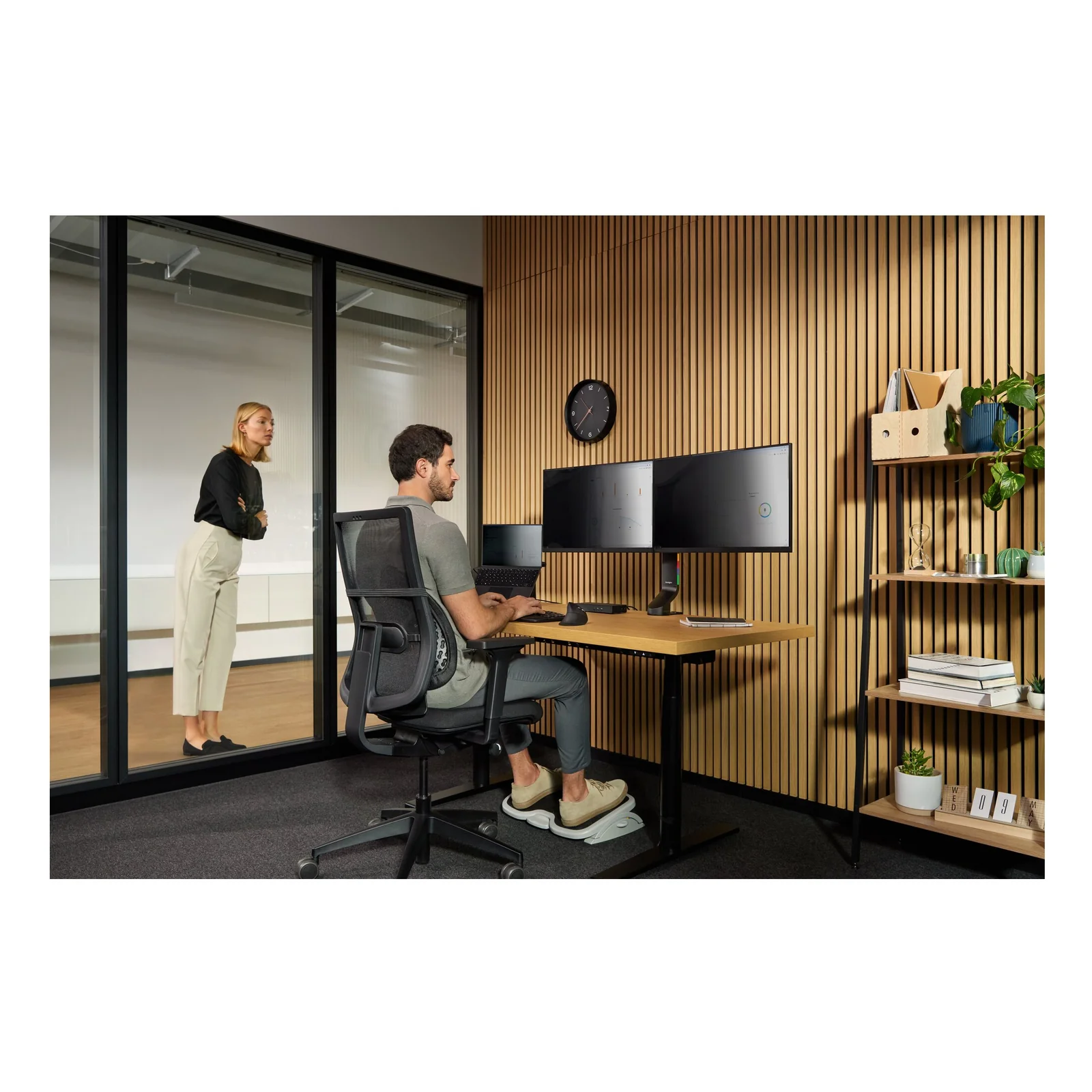 Vue large d'un bureau open space, deux personnes, double écran monté sur bras articulé