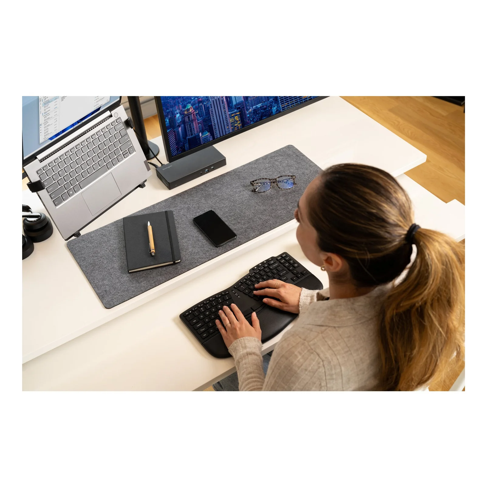 Vue de dessus, femme qui tape sur le clavier KB675 EQ, laptop surélevé et casque sur le bureau
