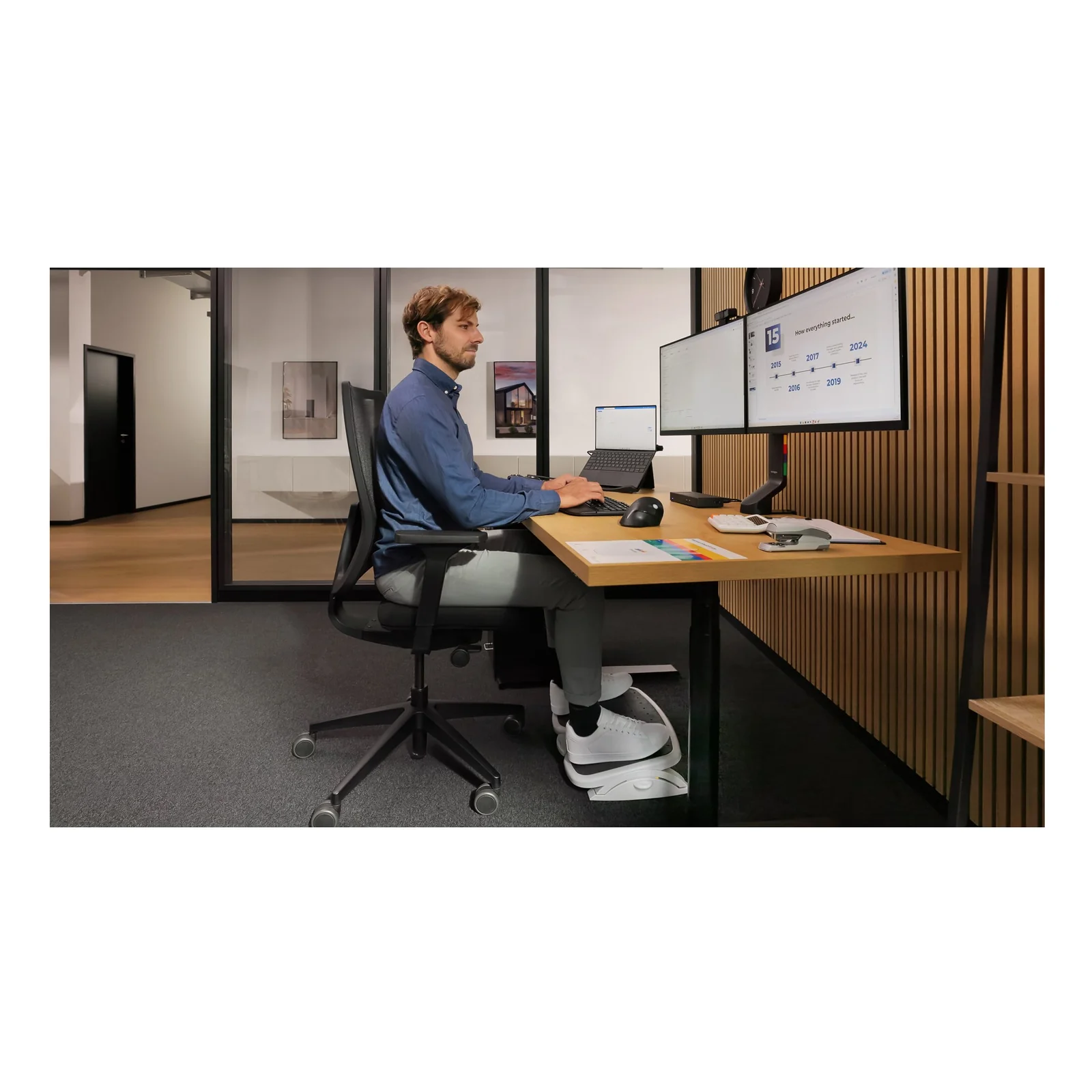 Homme assis avec repose-pieds devant un poste double moniteur, clavier ergonomique Kensington