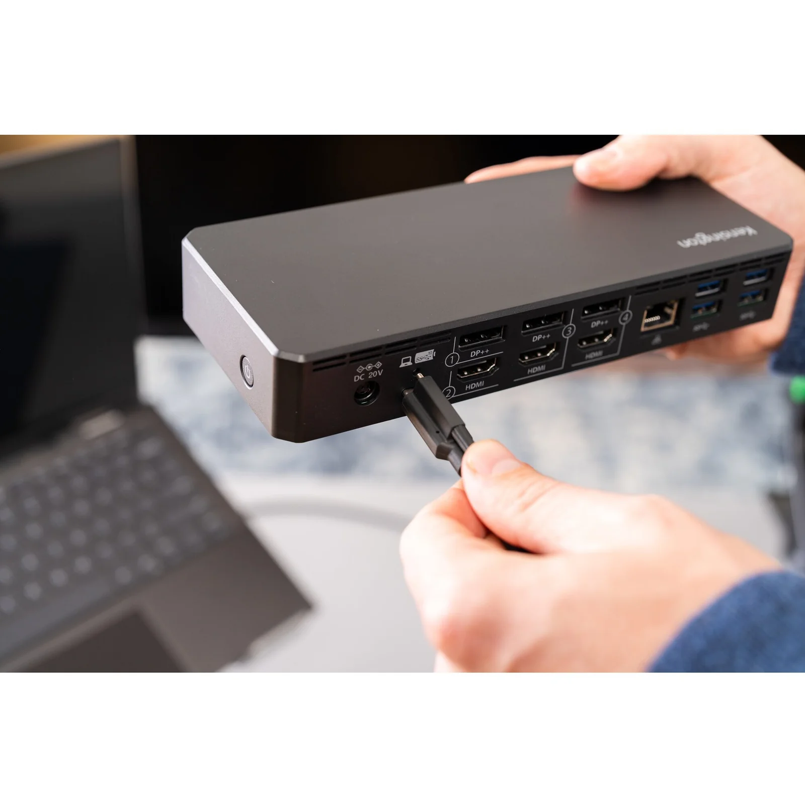 Main tenant la station Kensington SD4781P EQ et insérant un câble USB-C, vue de côté