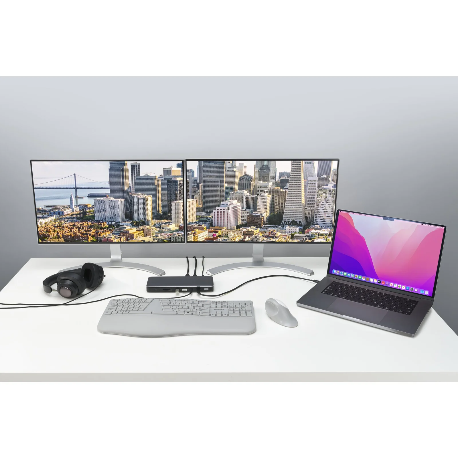 Station d'accueil SD5760T branchée à deux moniteurs et un MacBook sur bureau blanc, casque et clavier posés à côté