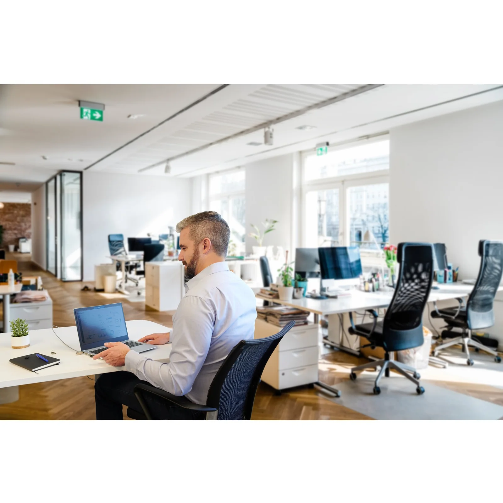 Homme travaillant dans un open-space, ordinateur portable sécurisé sur son bureau