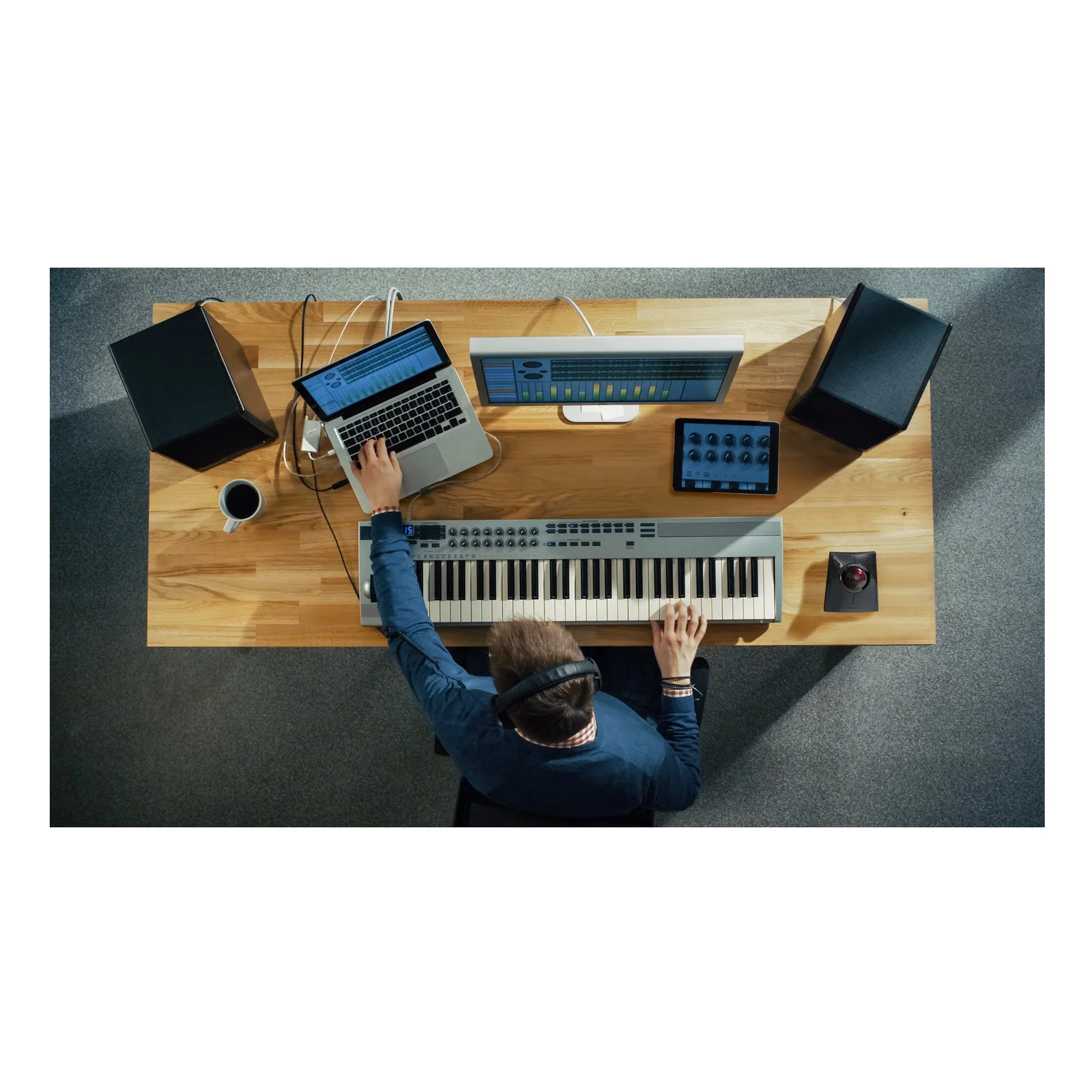 Vue aérienne, homme à un bureau avec clavier musical et ordinateur portable, trackball Kensington visible