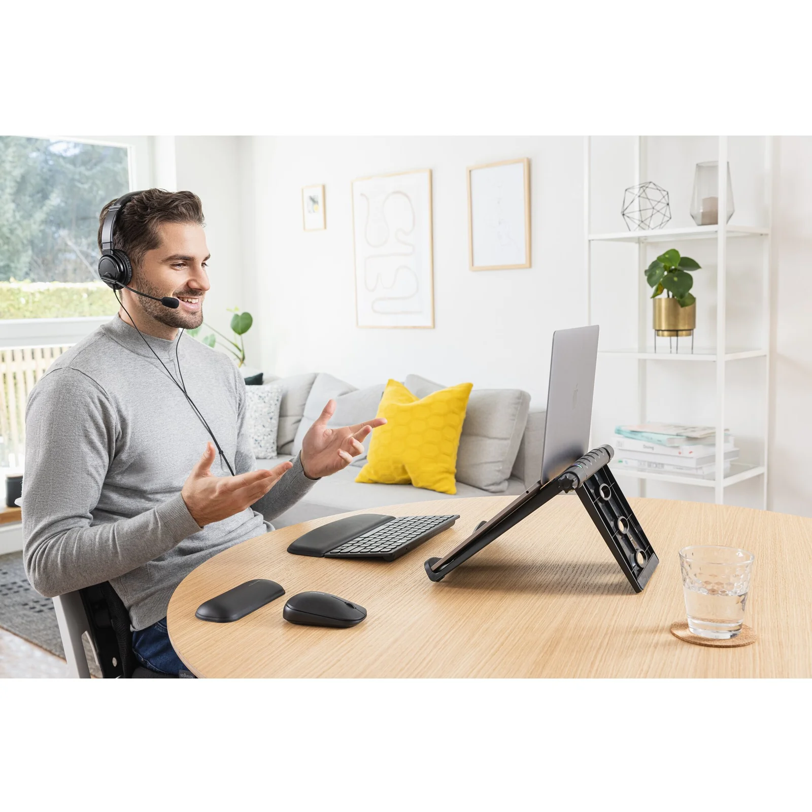 Personne en visioconférence, laptop posé sur rehausseur noir, casque audio sur les oreilles