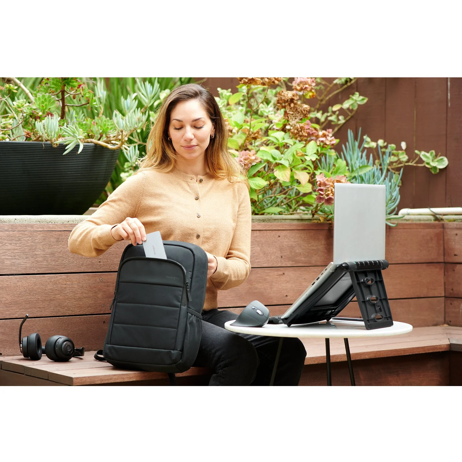 Femme en extérieur travaillant sur laptop posé sur un rehausseur compact