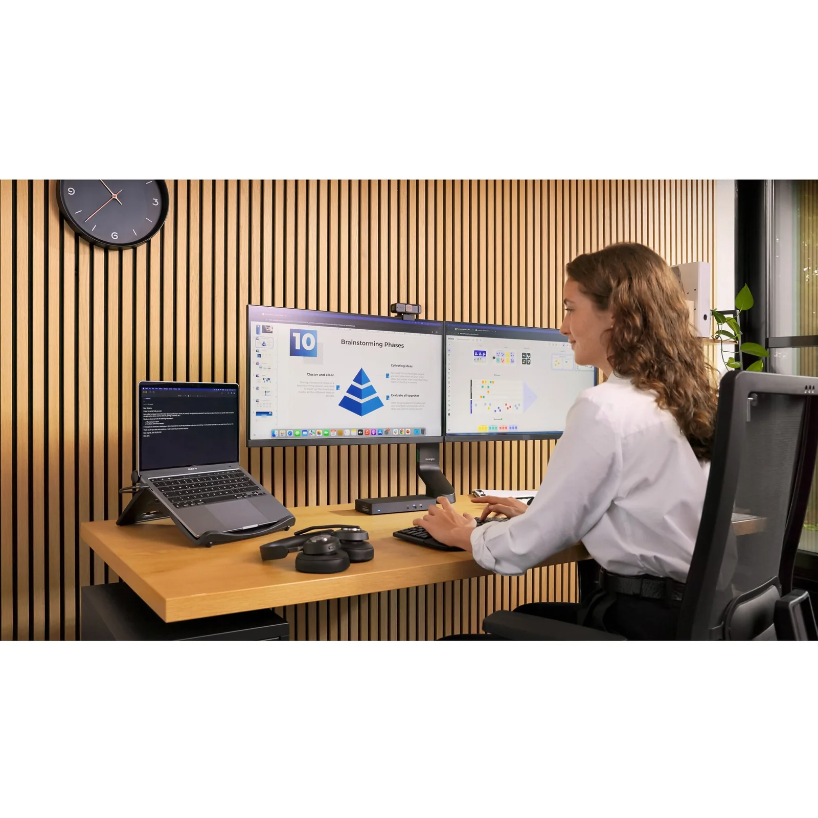 Femme au bureau avec double moniteur et laptop sur rehausseur, poste ergonomique