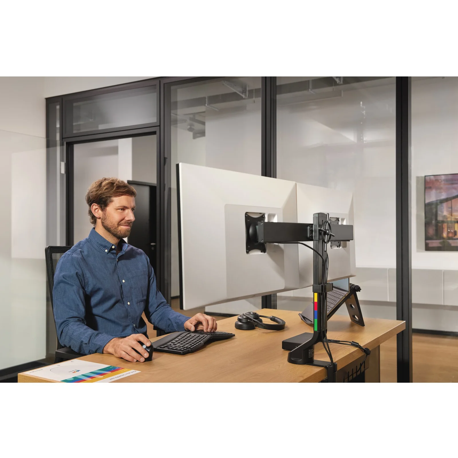 Homme ajustant un bras double moniteur au bureau debout blanc
