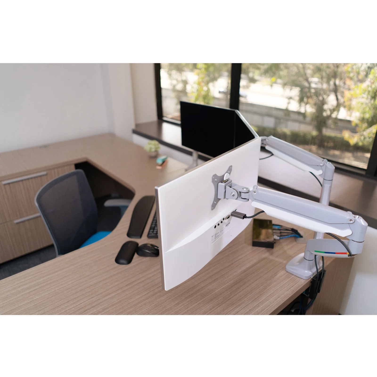 Vue plongeante, deux bras mono-écran sur bureau d'angle en open space lumineux