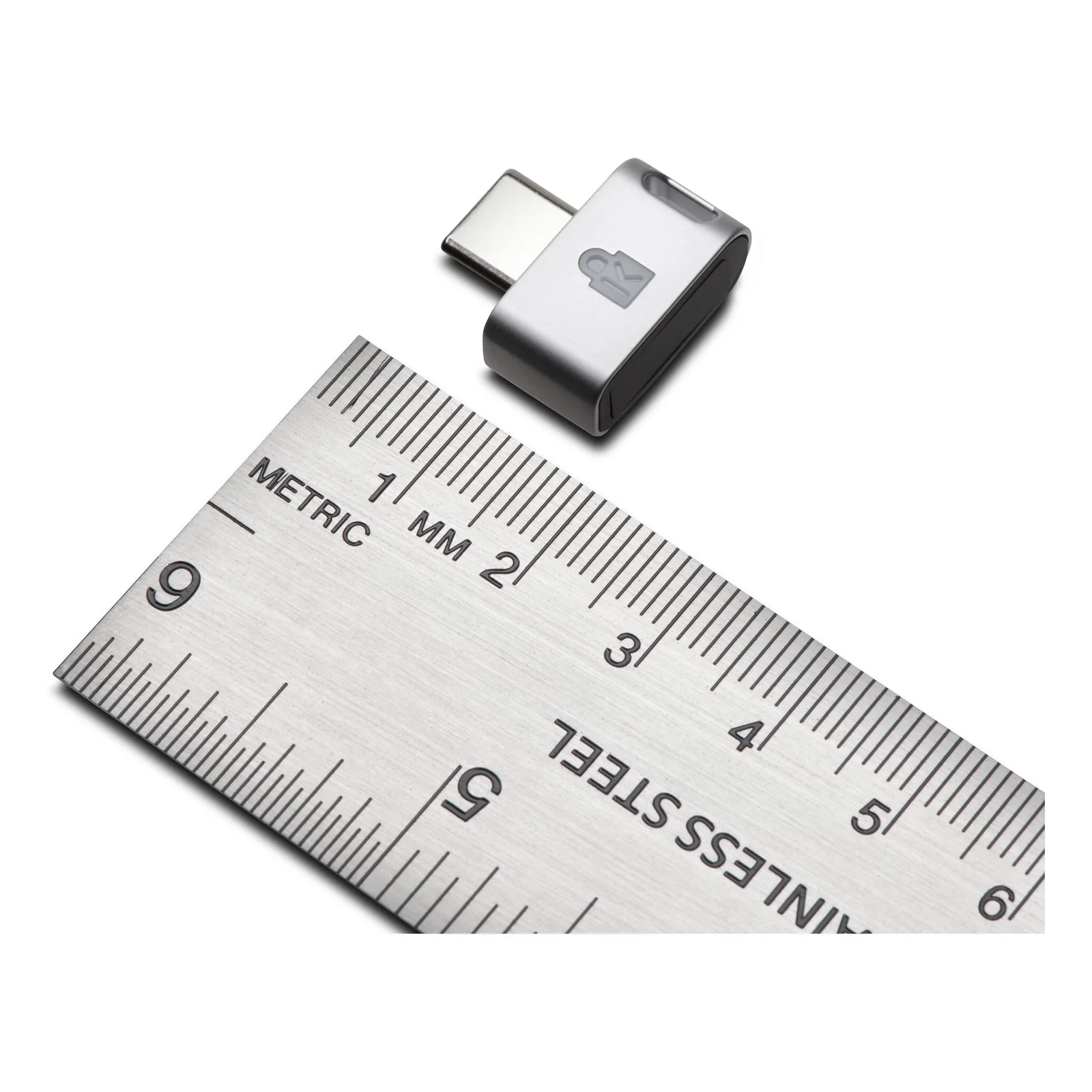 Clé Kensington VeriMark Guard posée sur une règle métrique, format ultra-compact visible