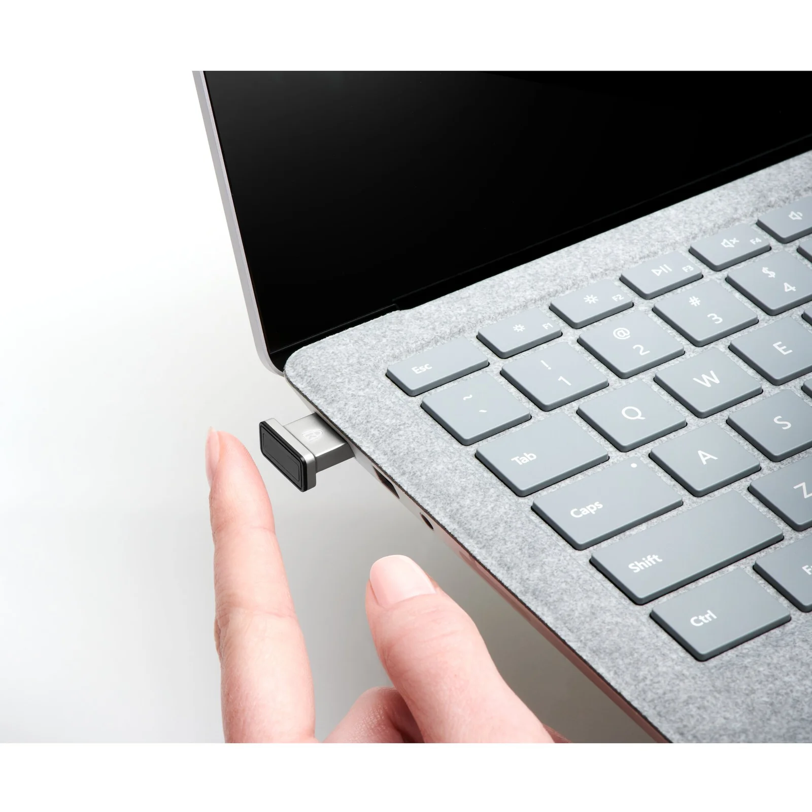 Doigt insérant la clé VeriMark IT dans le port USB latéral d'un laptop