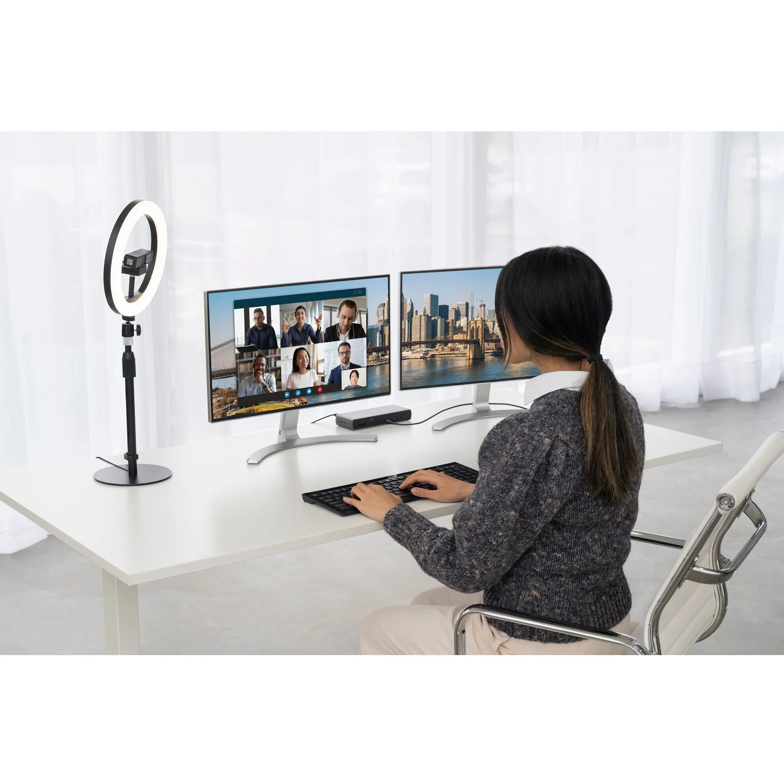 Personne en appel vidéo multi-participants, webcam fixée en haut du moniteur